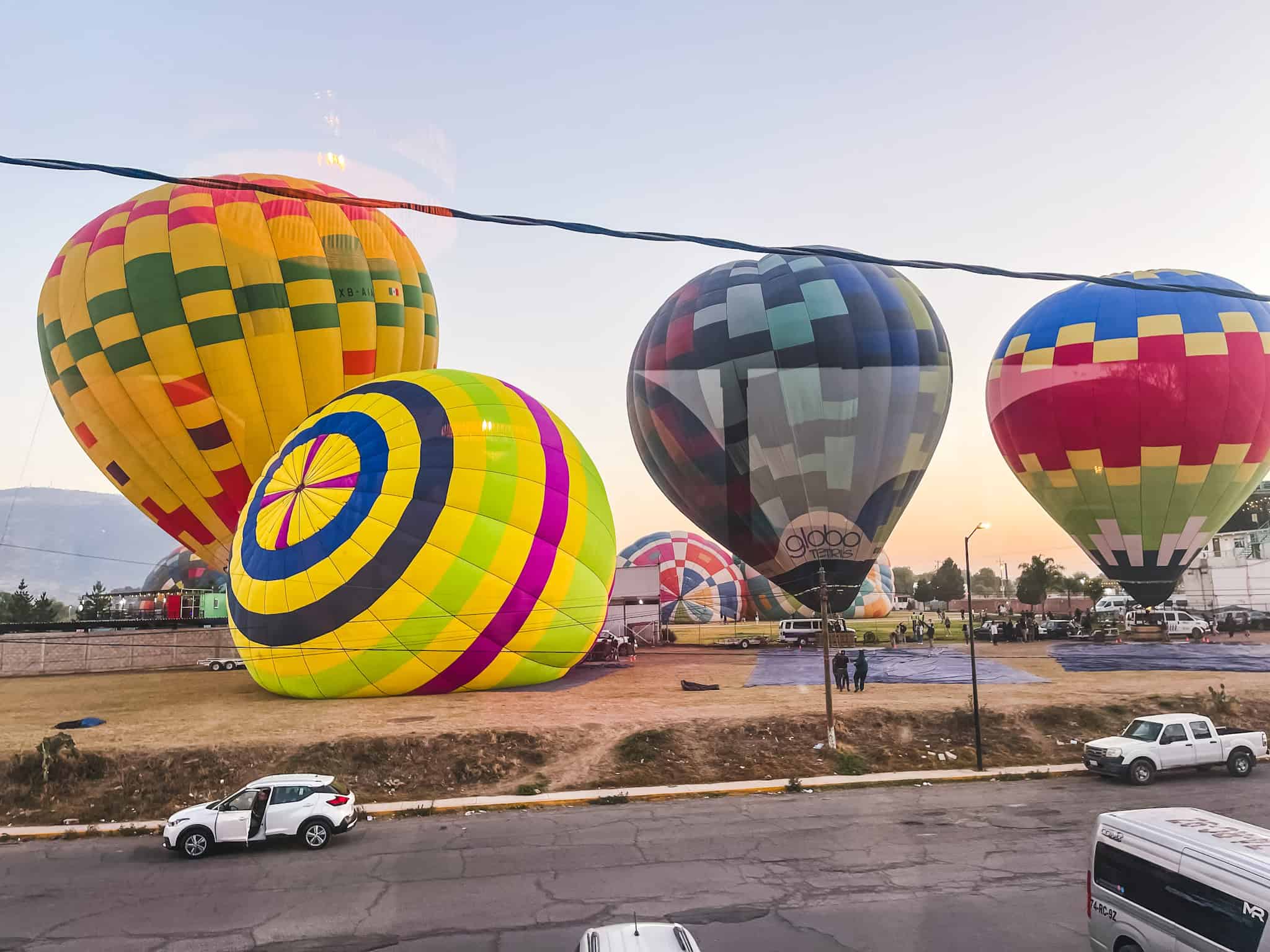 Hot air balloons launching from field near Mexico City pyramids