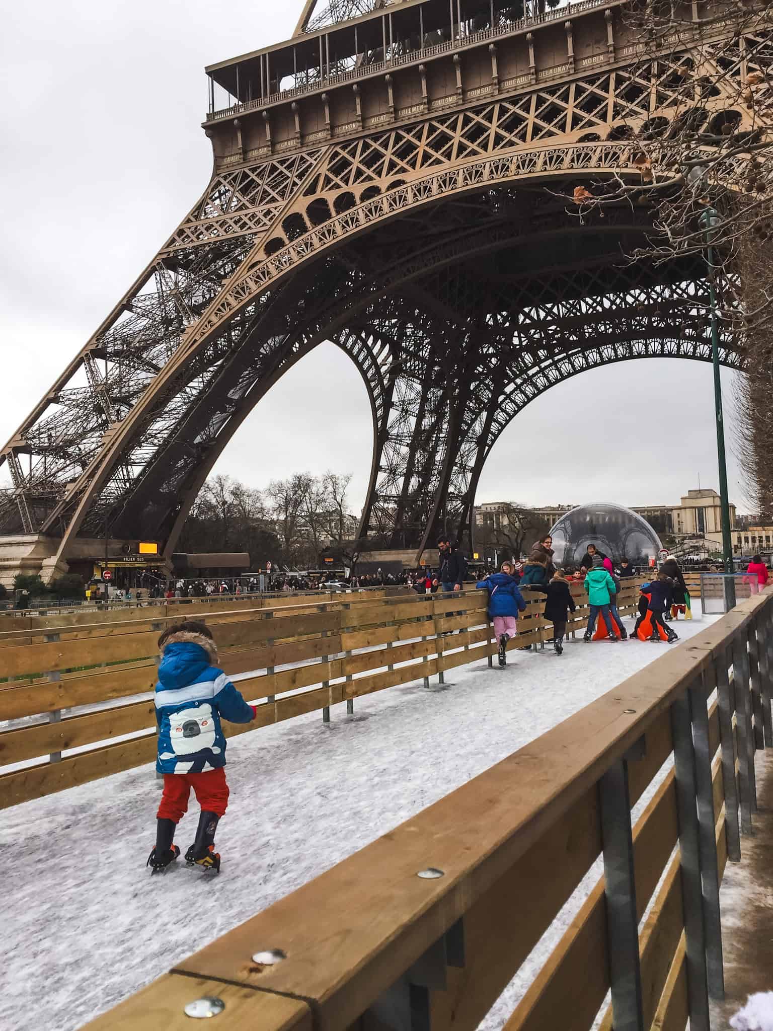 Kids ice skating beneath the Eiffel Tower, enjoying a classic Paris in winter activity.