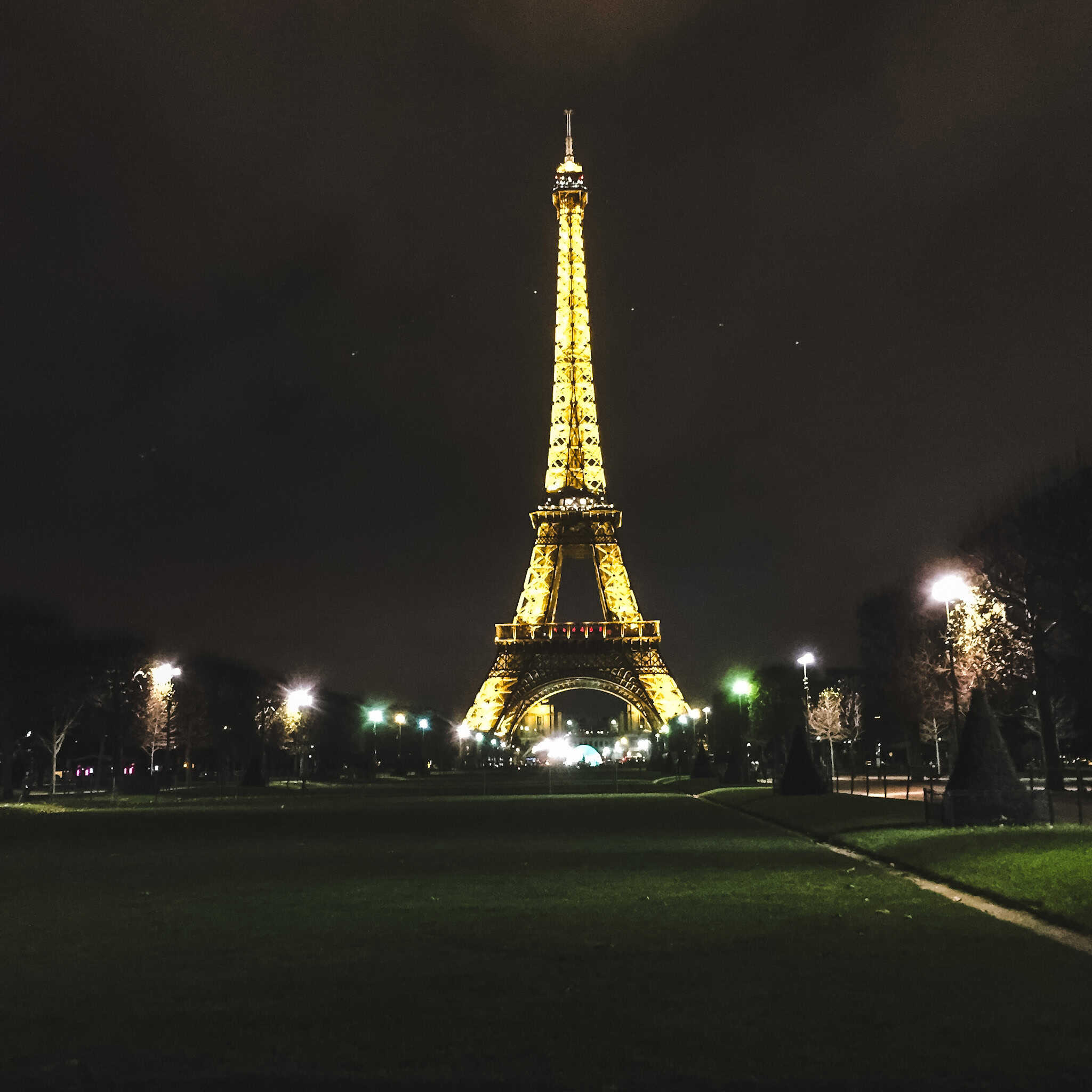 The Eiffel Tower illuminated against the night sky, glowing during a peaceful Paris in winter evening.