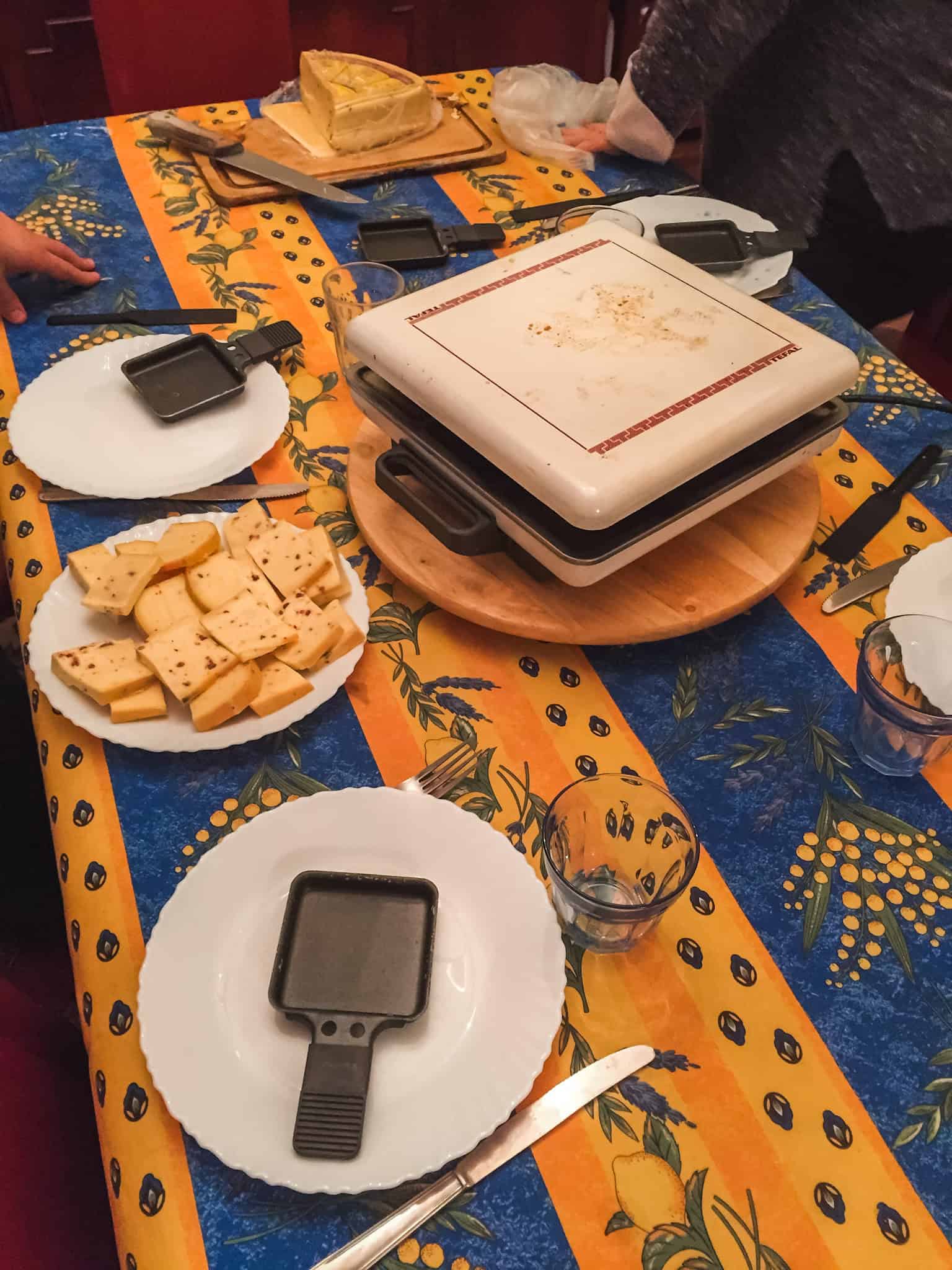 Cheese and charcuterie laid out for a traditional raclette dinner in a warm Paris apartment.