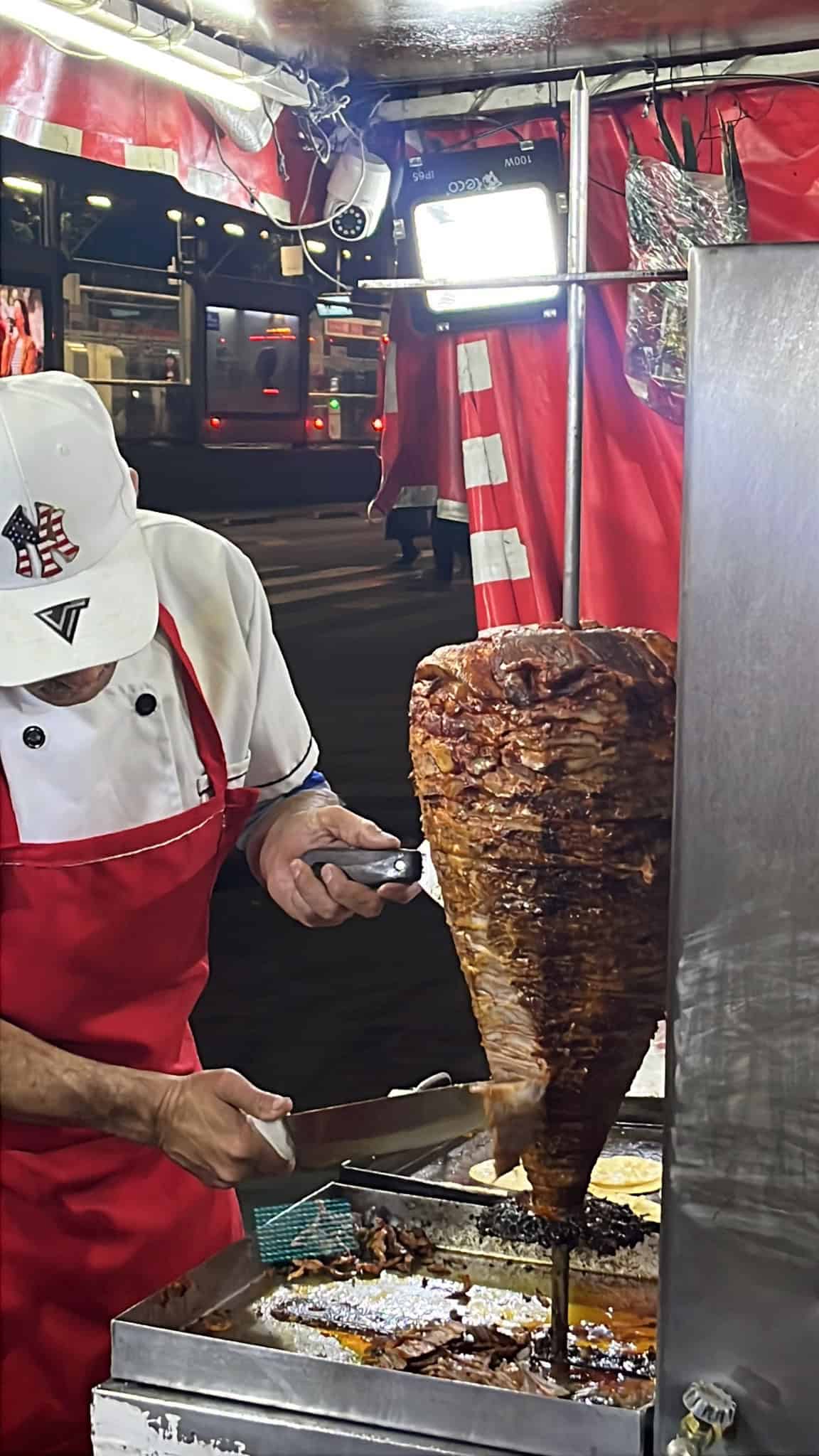 Street vendor slicing tacos al pastor straight from the spit in Mexico City