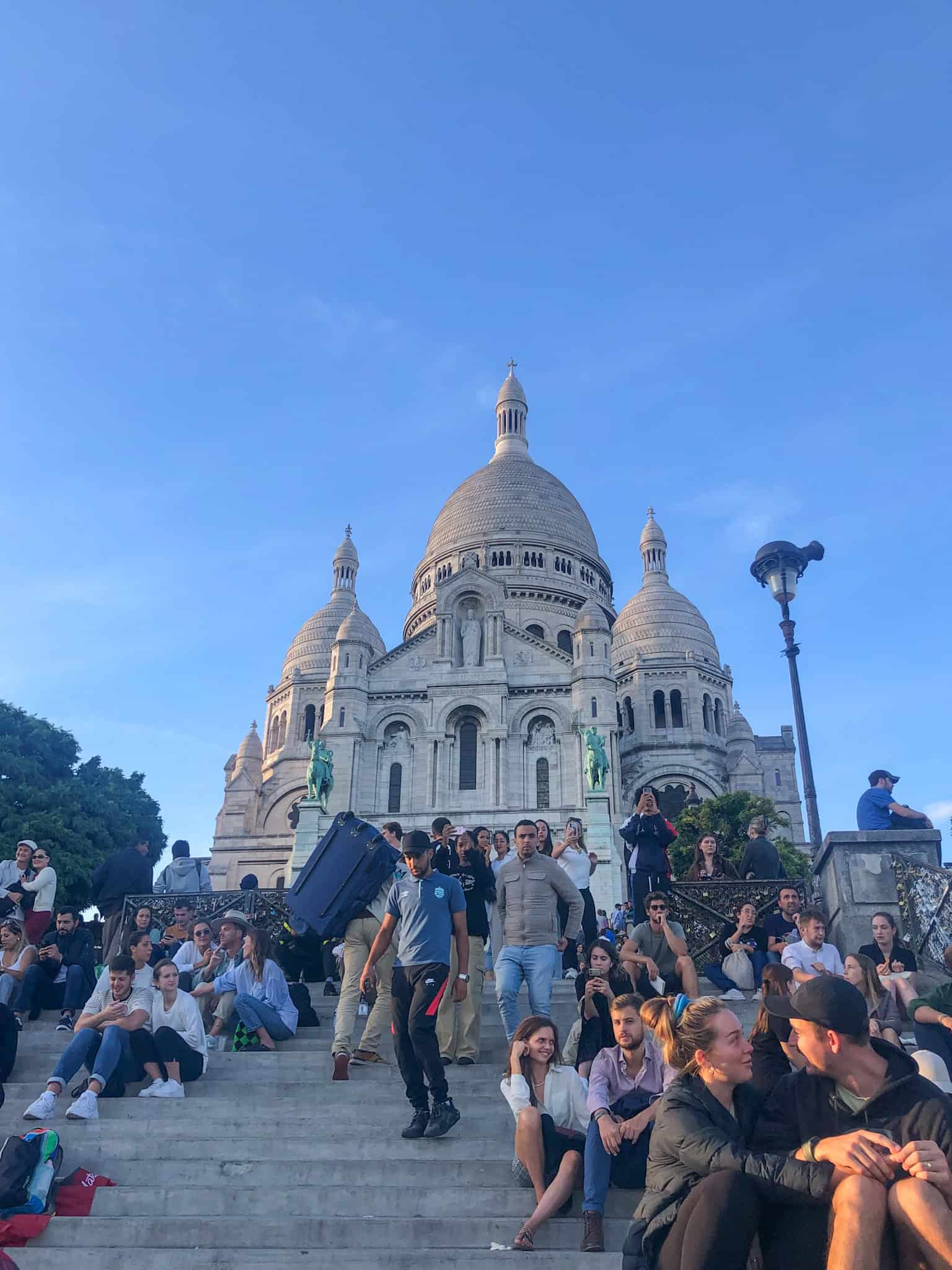sacre-coeur steps full of people at sunset in Paris in the fall
