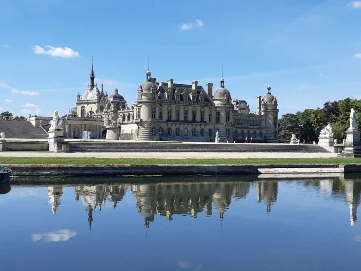 Château de Chantilly reflected in water with Renaissance architecture, easily reached on day trips from Paris by train