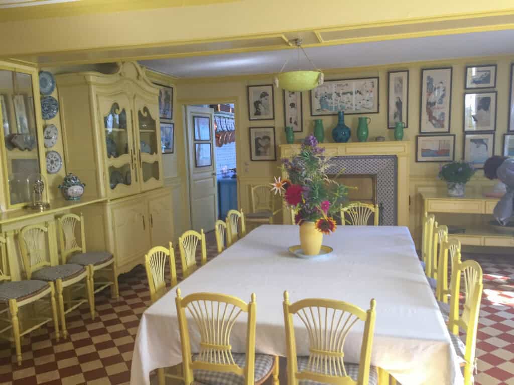 Monet's yellow dining room interior at Giverny house showing period furniture and artwork, accessible via day trips from Paris by train