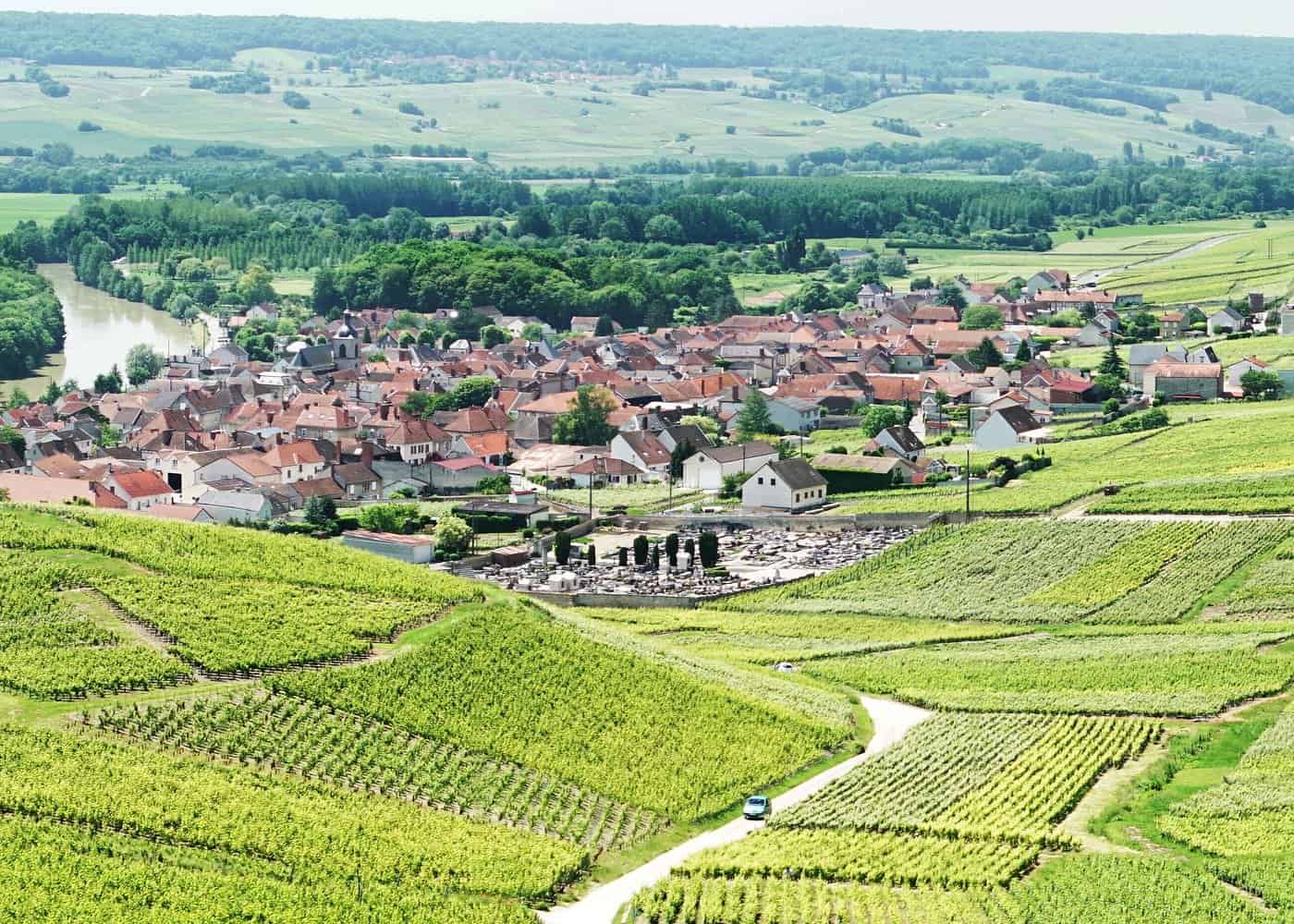 Aerial view of a charming French village nestled among rolling Champagne vineyards, perfect for day trips from Paris wine tours