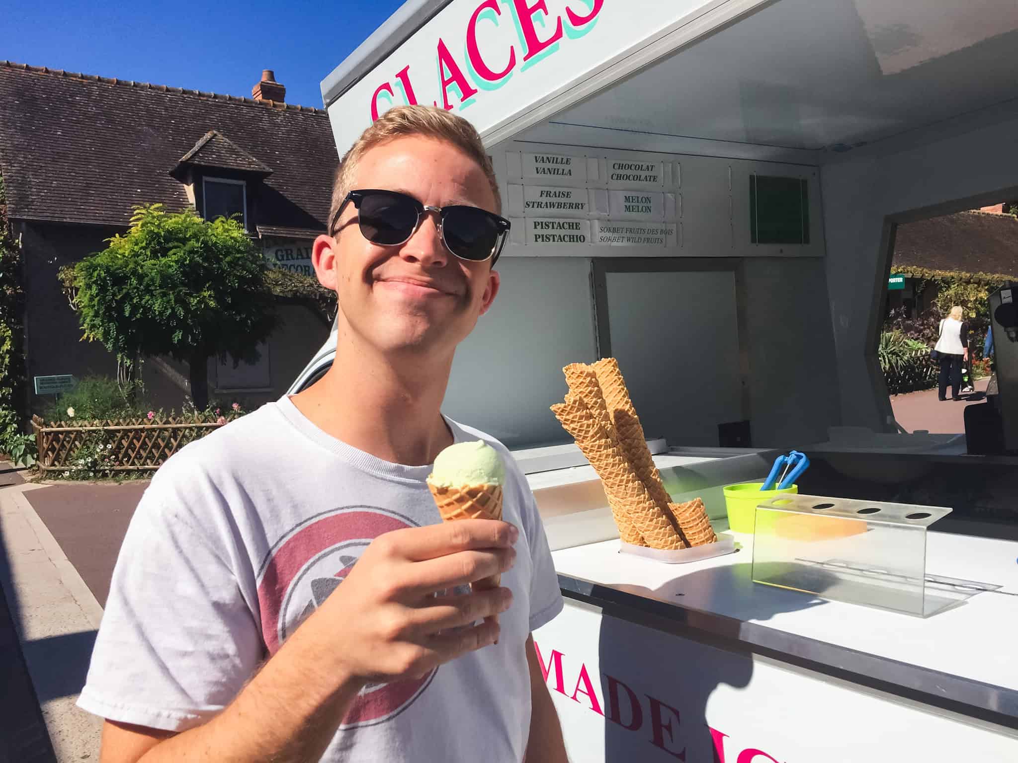 Tourist enjoying artisanal French ice cream from a traditional "glaces" vendor stand on a sunny day
