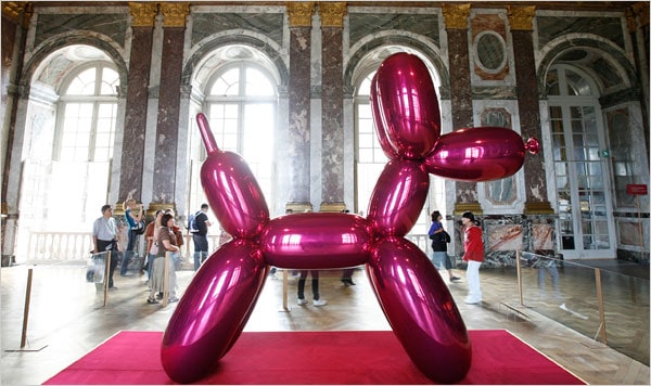 Jeff Koons' iconic pink balloon dog sculpture displayed in the opulent Hall of Mirrors at Versailles, blending contemporary art with classical French architecture during day trips from Paris