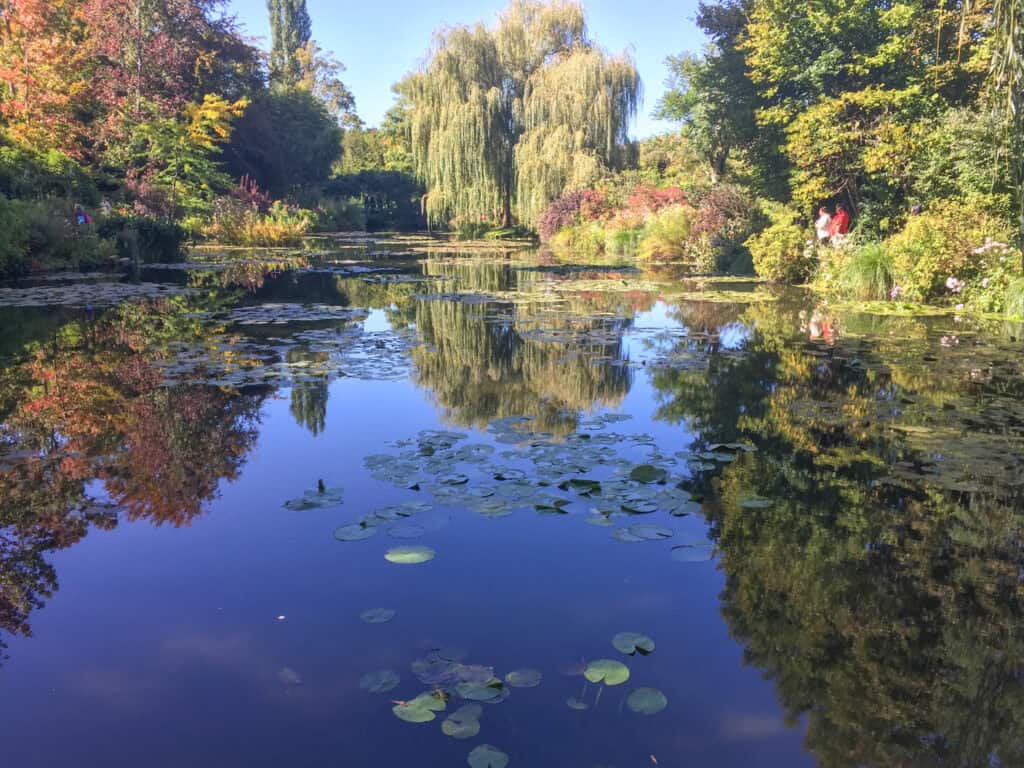 Monet's famous water lily pond in Giverny with floating lily pads, weeping willow trees, and perfect reflections