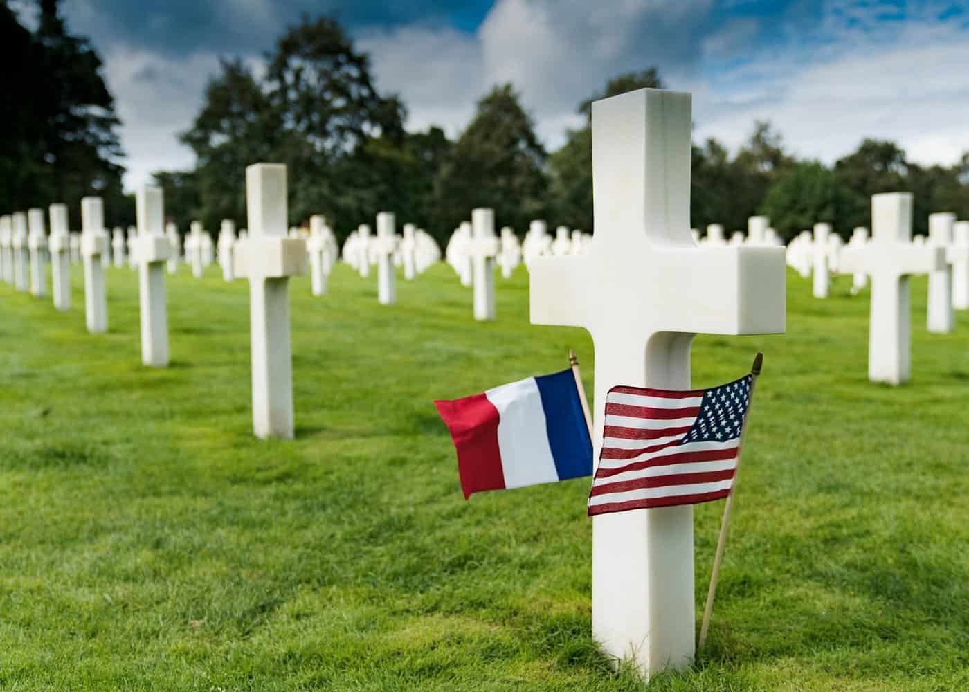 Solemn military cemetery with white crosses and French and American flags honoring fallen soldiers