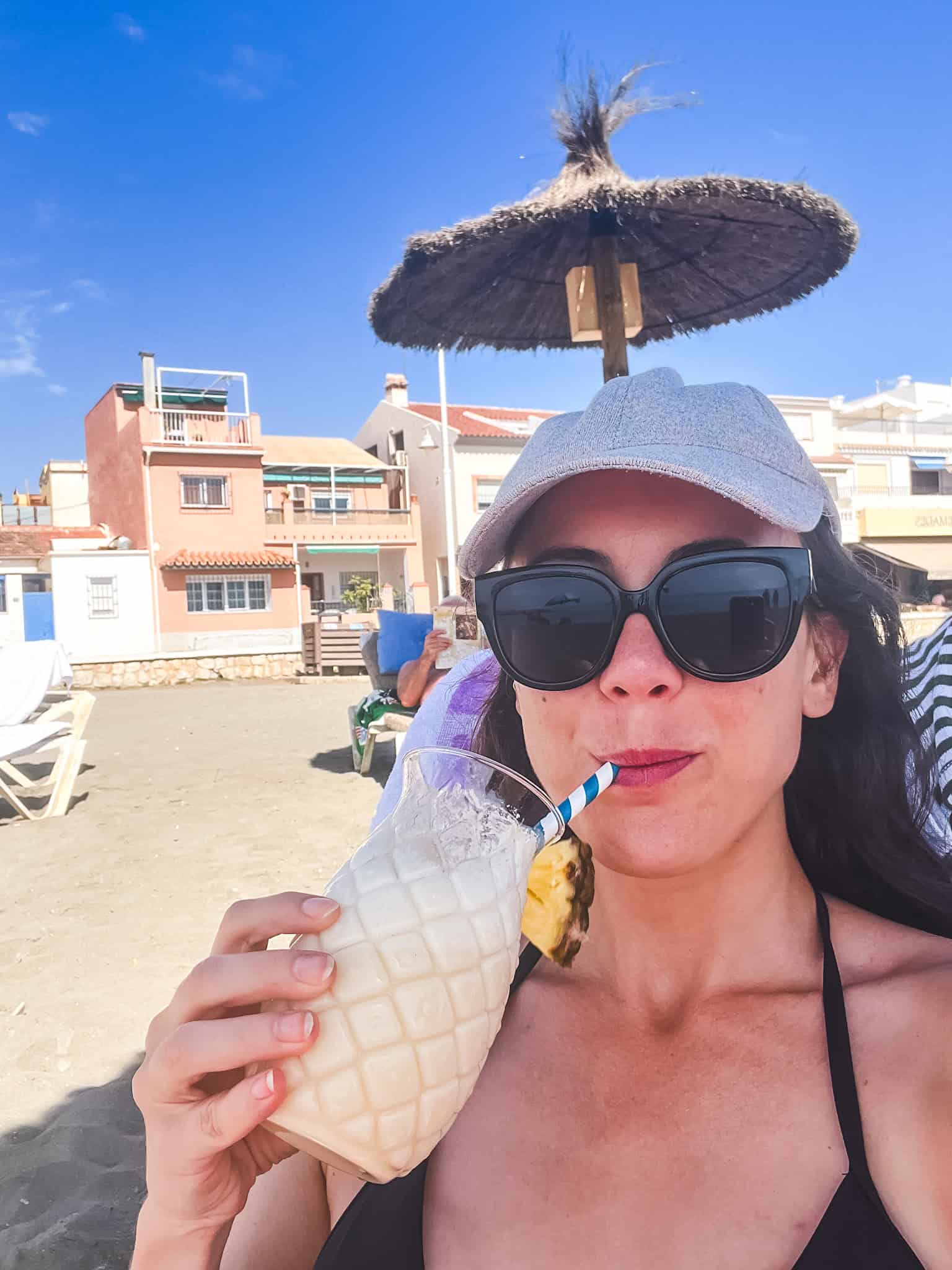 Woman enjoying pineapple cocktail on malaga beach, relaxing what to do in malaga