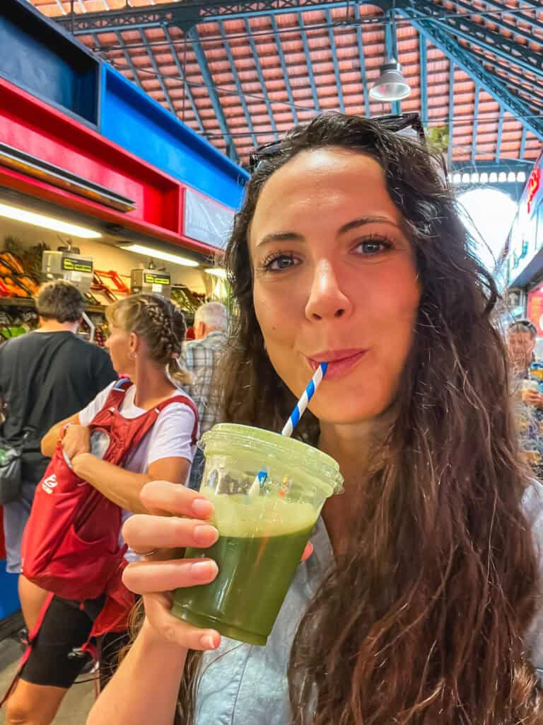 Woman with green juice at vibrant Mercado de Atarazanas, popular things to do in malaga