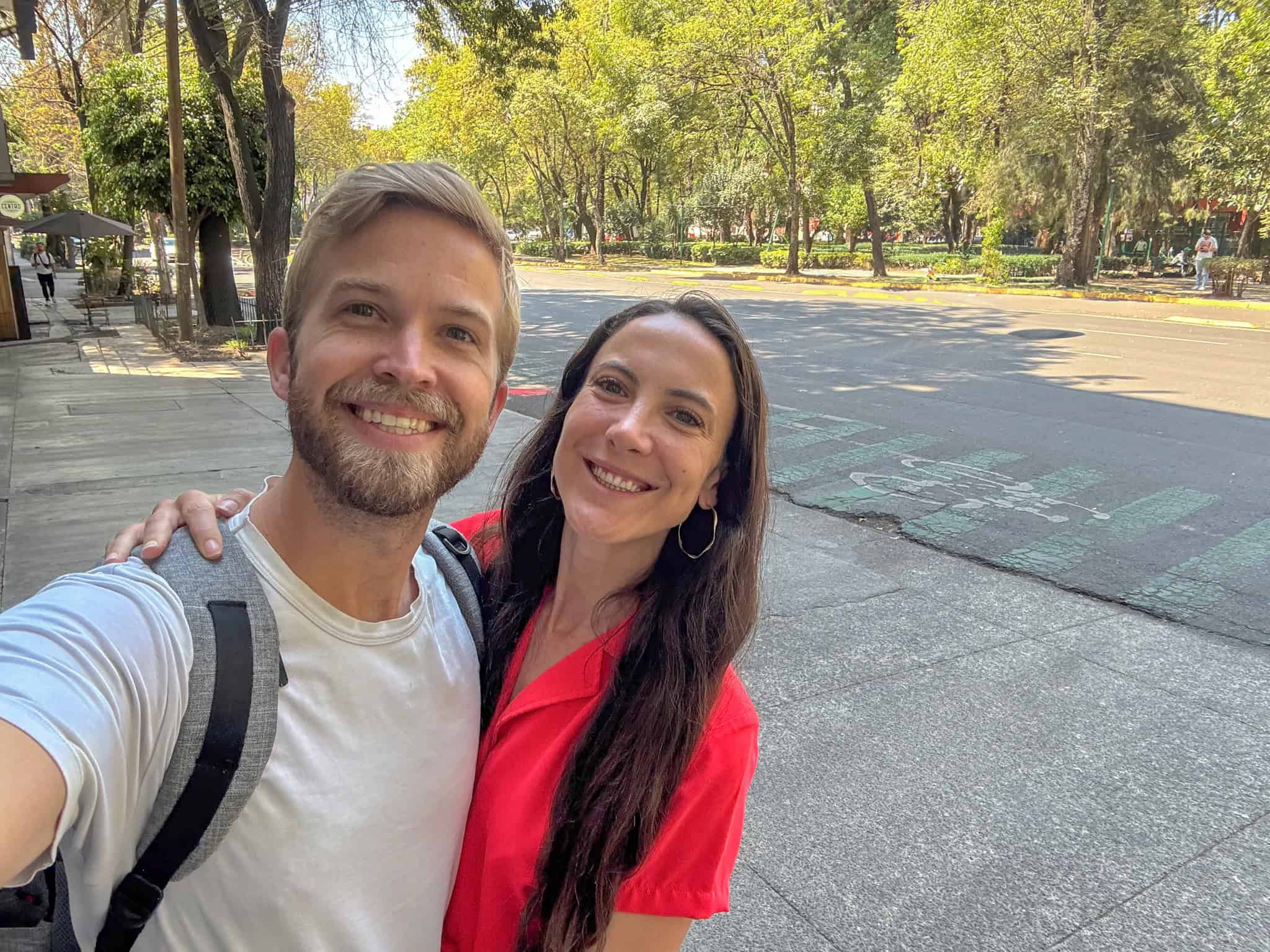 Couple taking selfie in tree-lined plaza or park area in Mexico City
