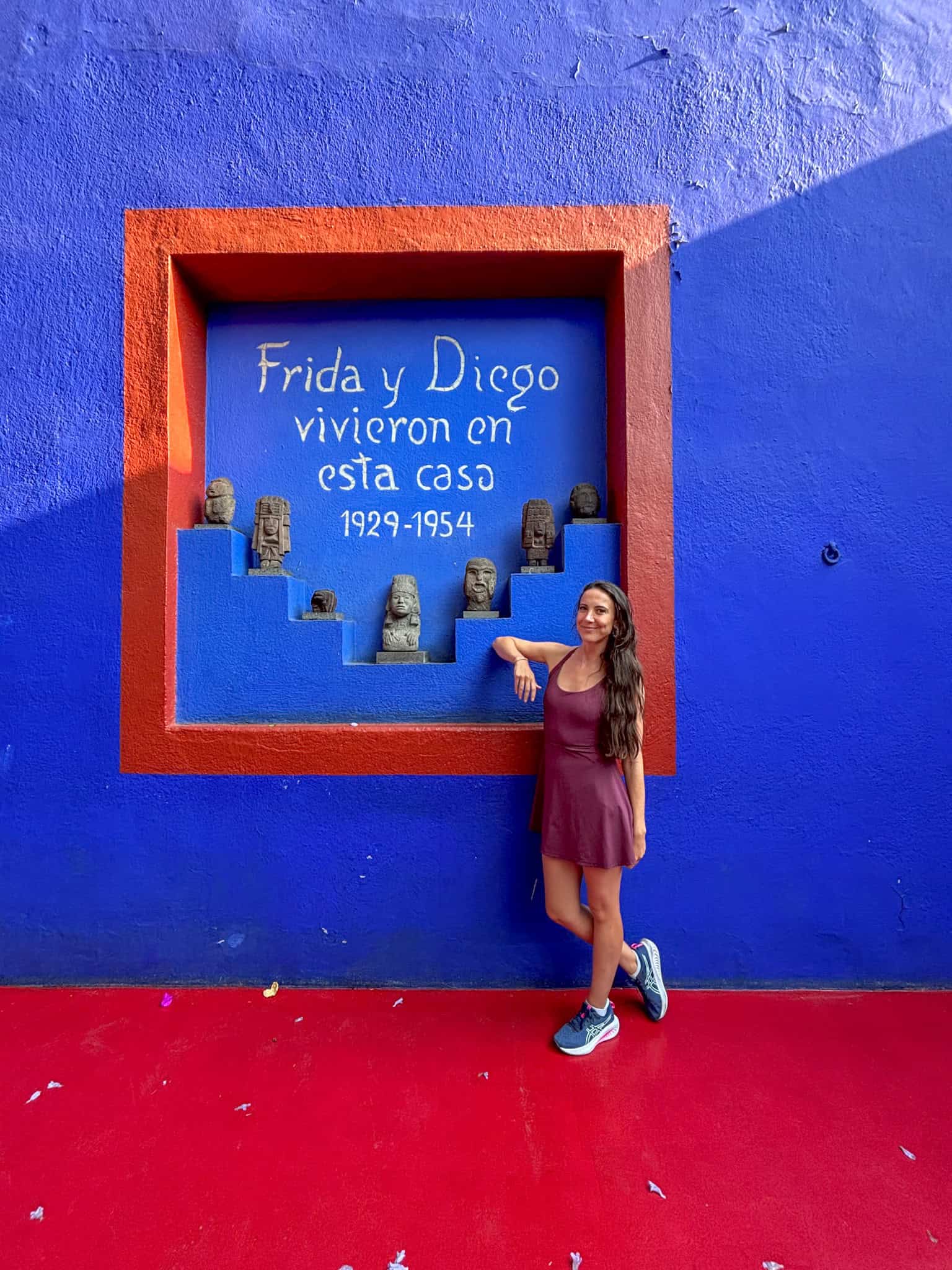 Woman posing next to colorful blue wall display at Frida Kahlo Museum Casa Azul, showing what to do in Mexico City for art lovers