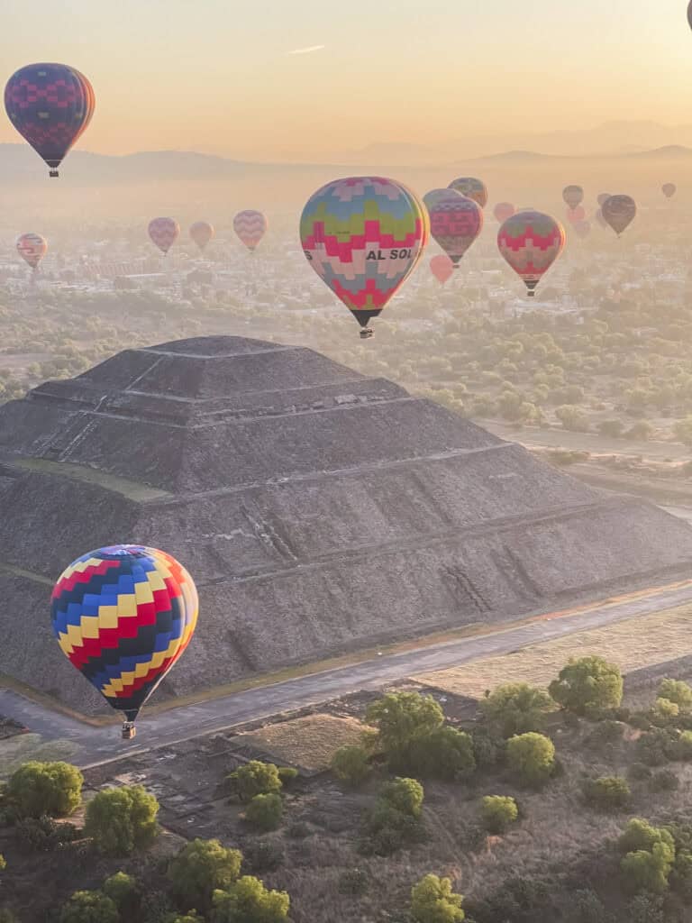 Hot air balloons floating over Teotihuacan pyramids at sunrise, demonstrating what to do in Mexico City day trips