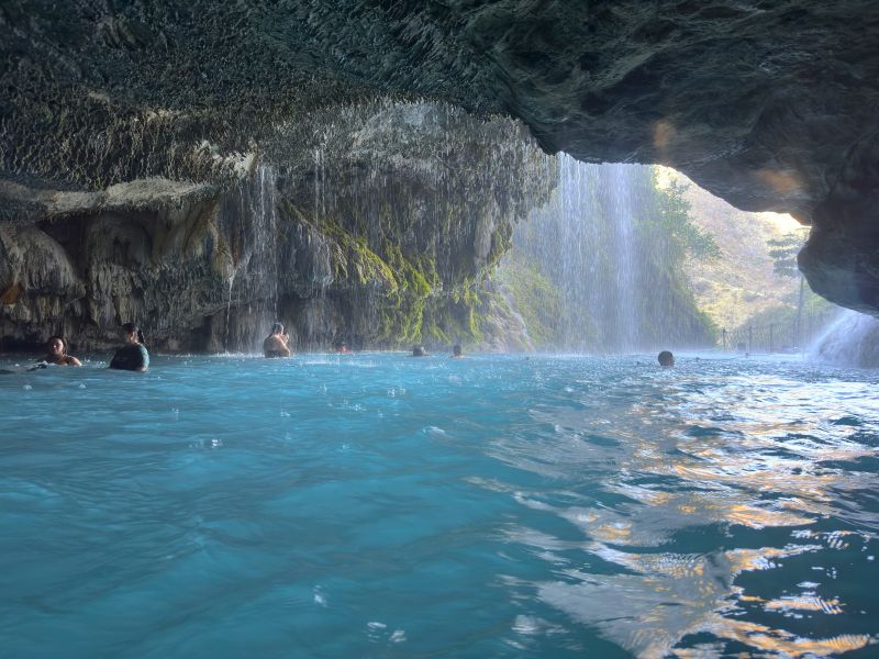 Visitors swimming inside the main grotto at Grutas de Tolantongo with natural waterfall and thermal pool