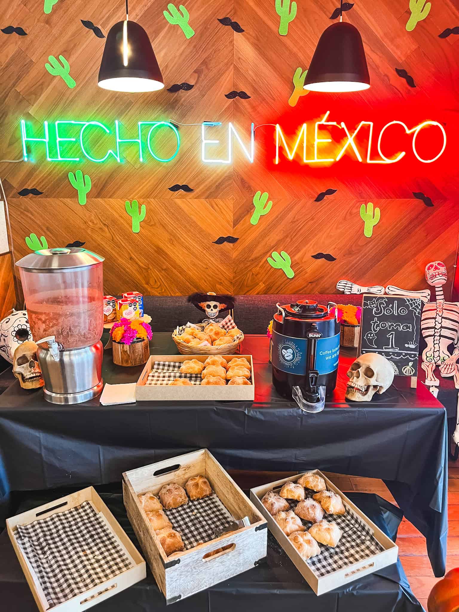 Day of the Dead themed display with "HECHO EN MEXICO" neon sign and traditional Mexican pastries during the best time to visit Mexico City in October for Dia de los Muertos celebrations, featuring skulls, cactus decorations, and seasonal breadRetryClaude can make mistakes. Please double-check responses.Research Sonnet 4