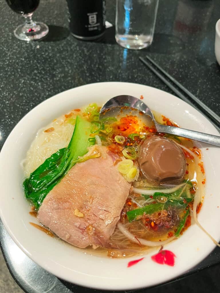 Traditional beef noodle soup served in Taiwan airport lounge with chopsticks and wine glass
