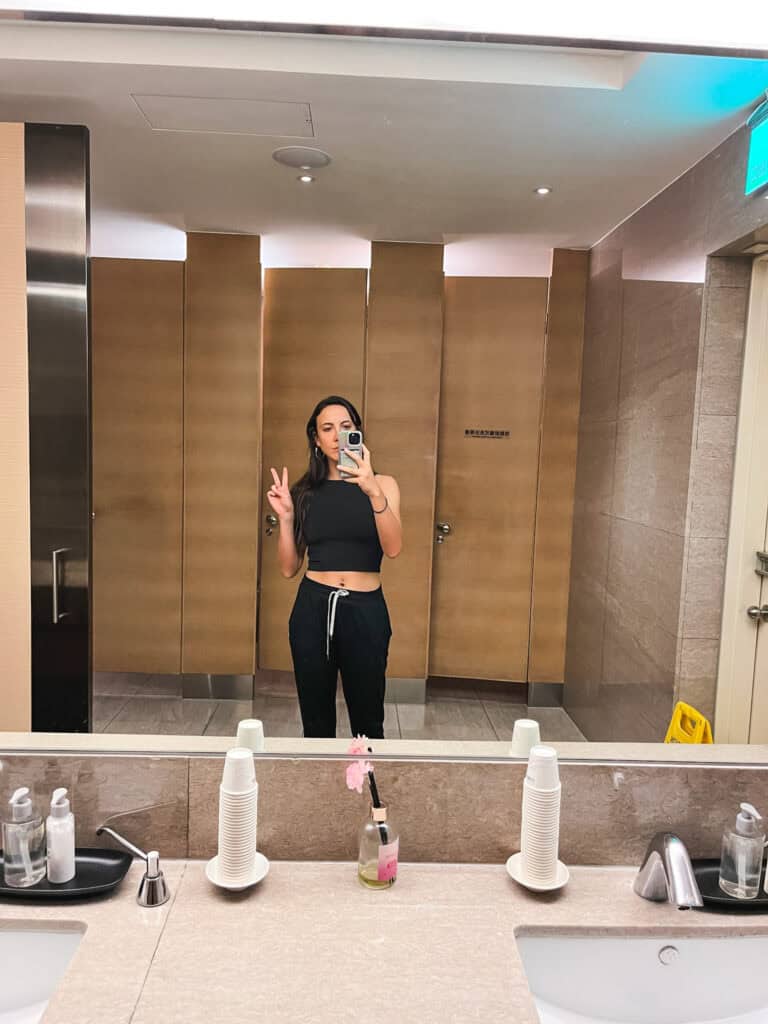 Passenger taking mirror selfie in modern airport lounge bathroom facilities