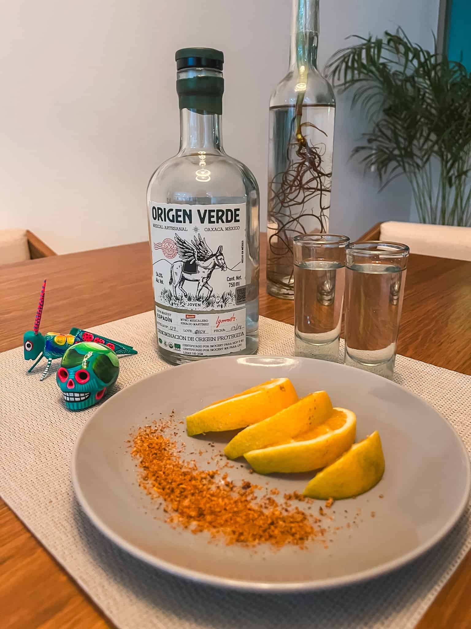 Origen Verde mezcal bottle with traditional orange slices and chili powder setup, showcasing Mexican spirits culture appreciated by both locals and visitors amid Mexico City protests debates
