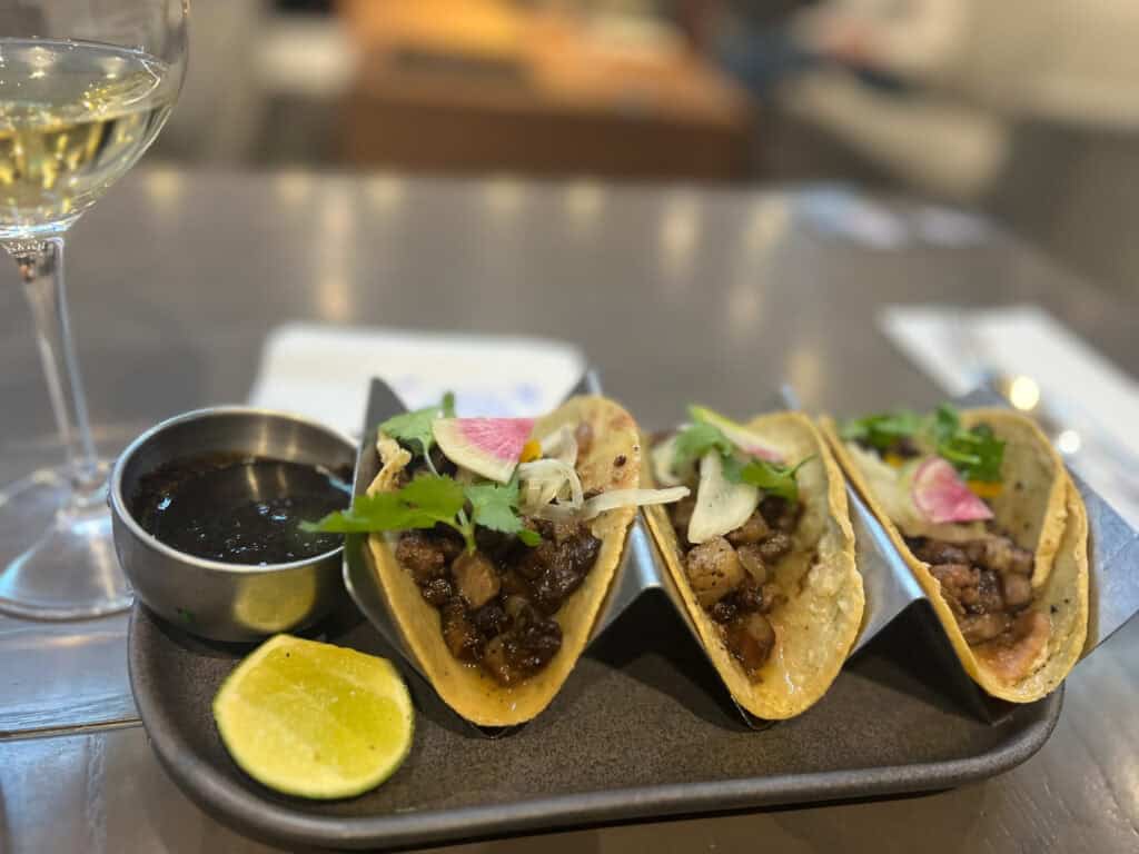 Elegant taco presentation with wine, exemplifying Mexico City's evolving food scene that's central to discussions around tourism impacts raised in recent protests