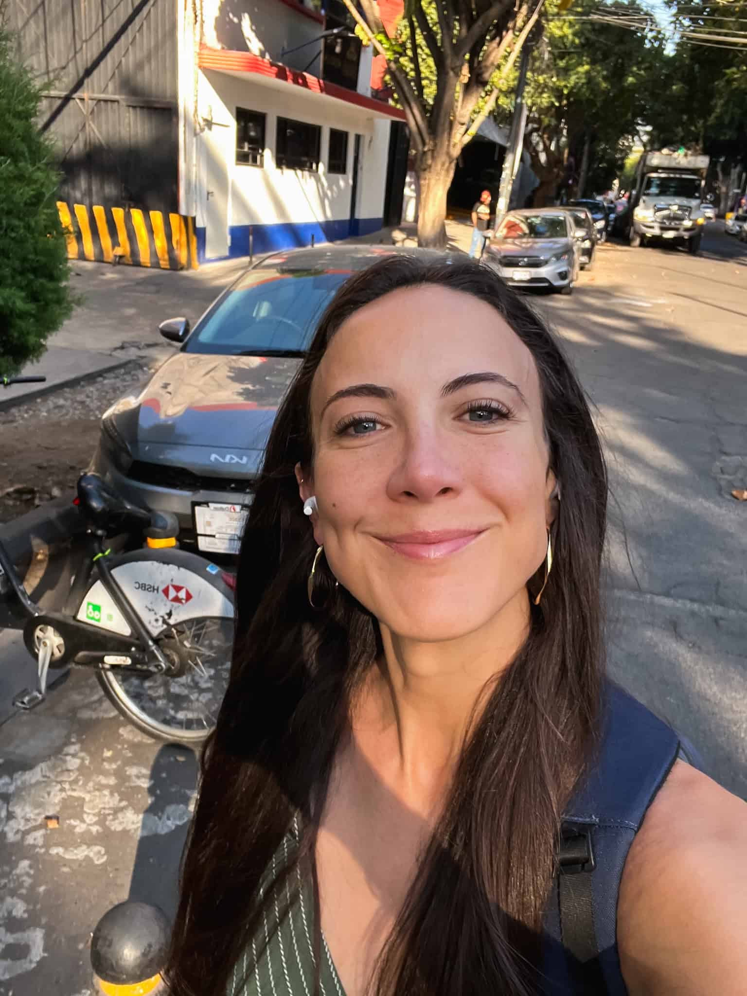 Woman taking selfie on Mexico City street with bike-share bikes visible, capturing the everyday life experience that's been affected by the issues behind recent Mexico City protests