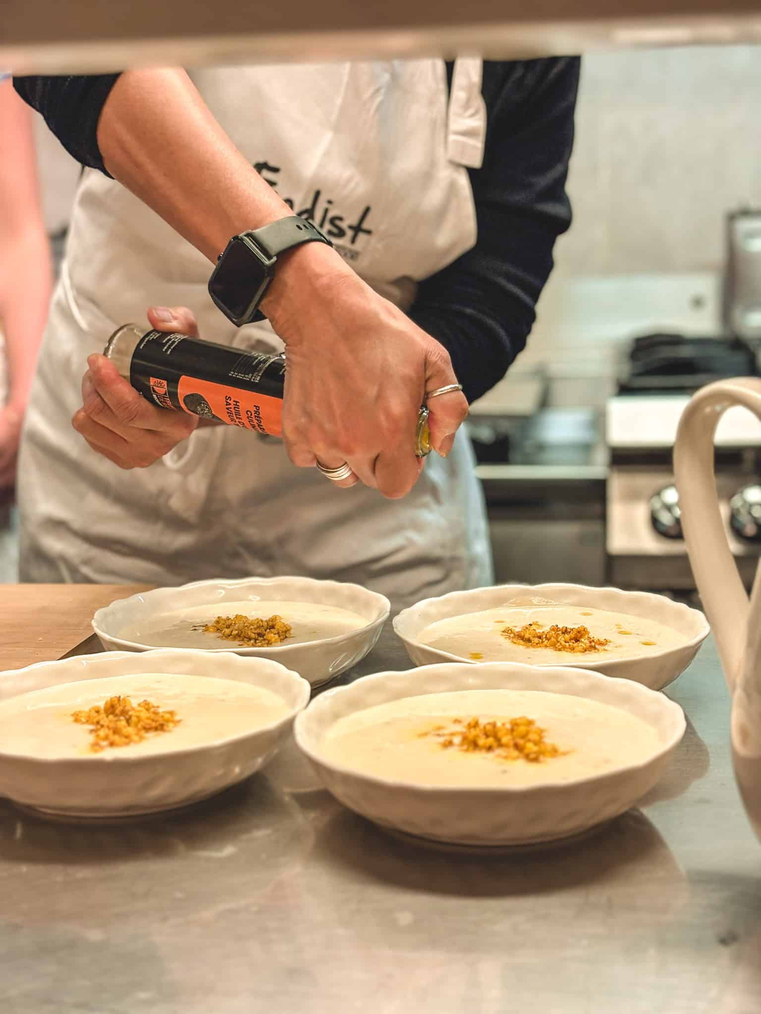 Finishing soup with truffle oil drizzle and toppings at cooking class in Paris