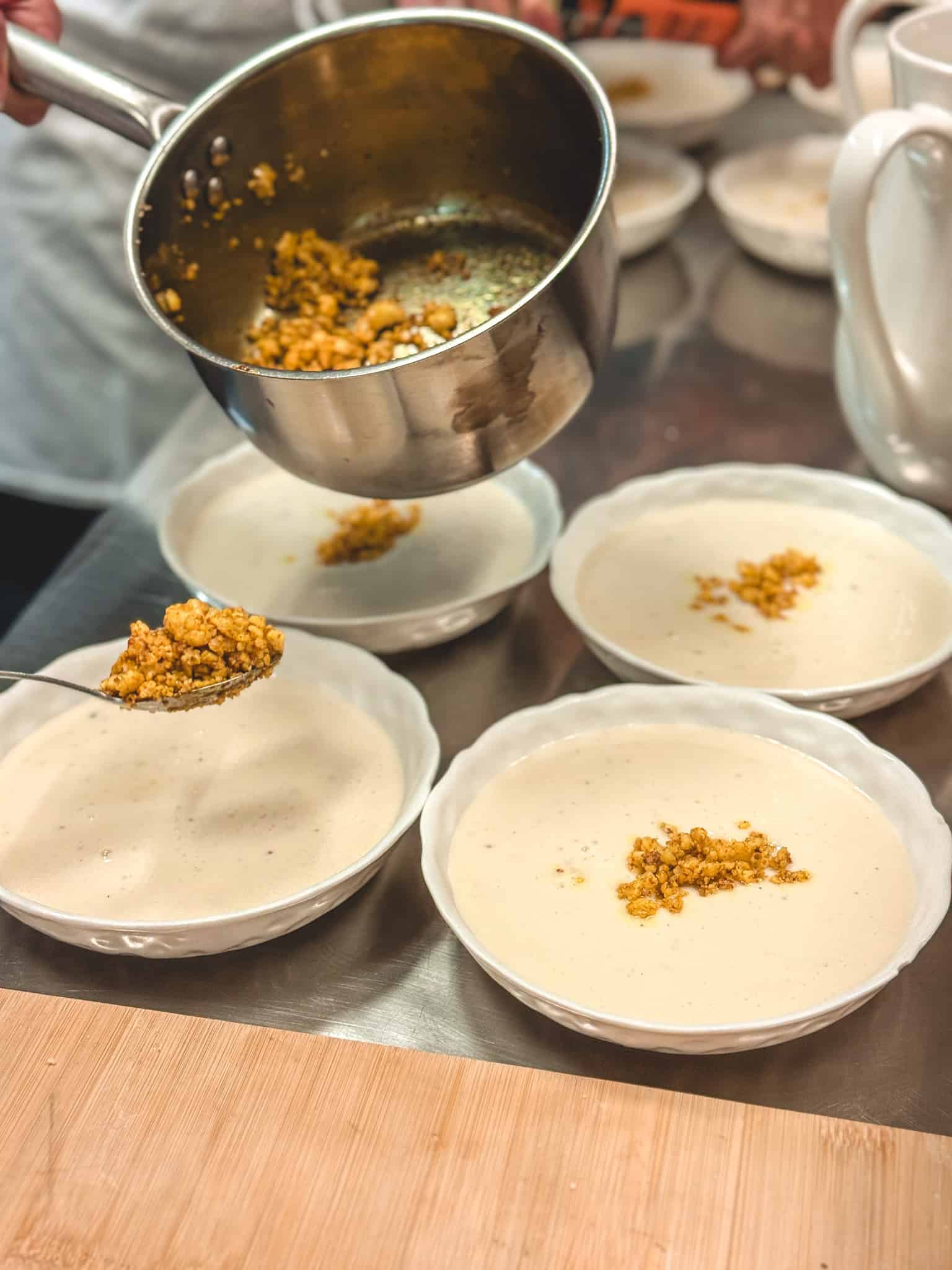 Garnishing soup with toasted cauliflower crumble at cooking class in Paris