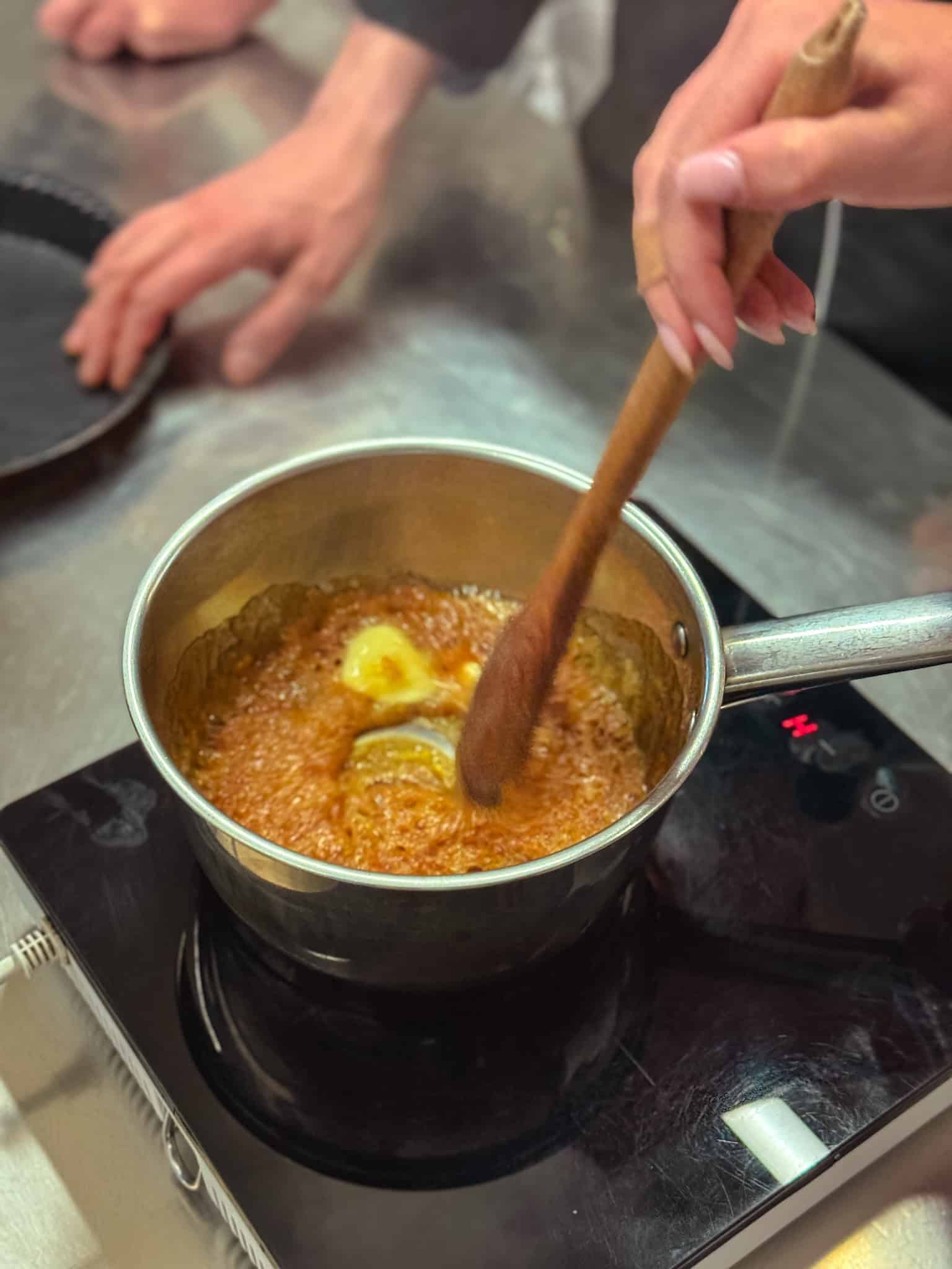 Making French caramel sauce with wooden spoon at Paris cooking workshop