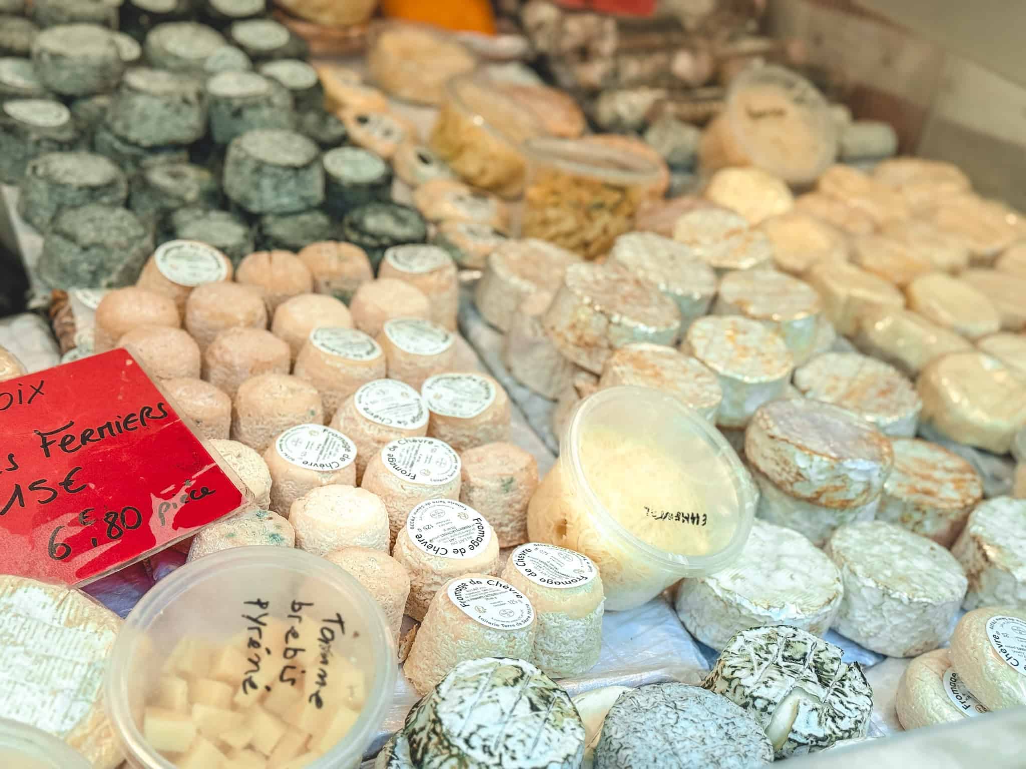 Artisanal French cheeses including fromage de chèvre displayed at cooking class in Paris market tour