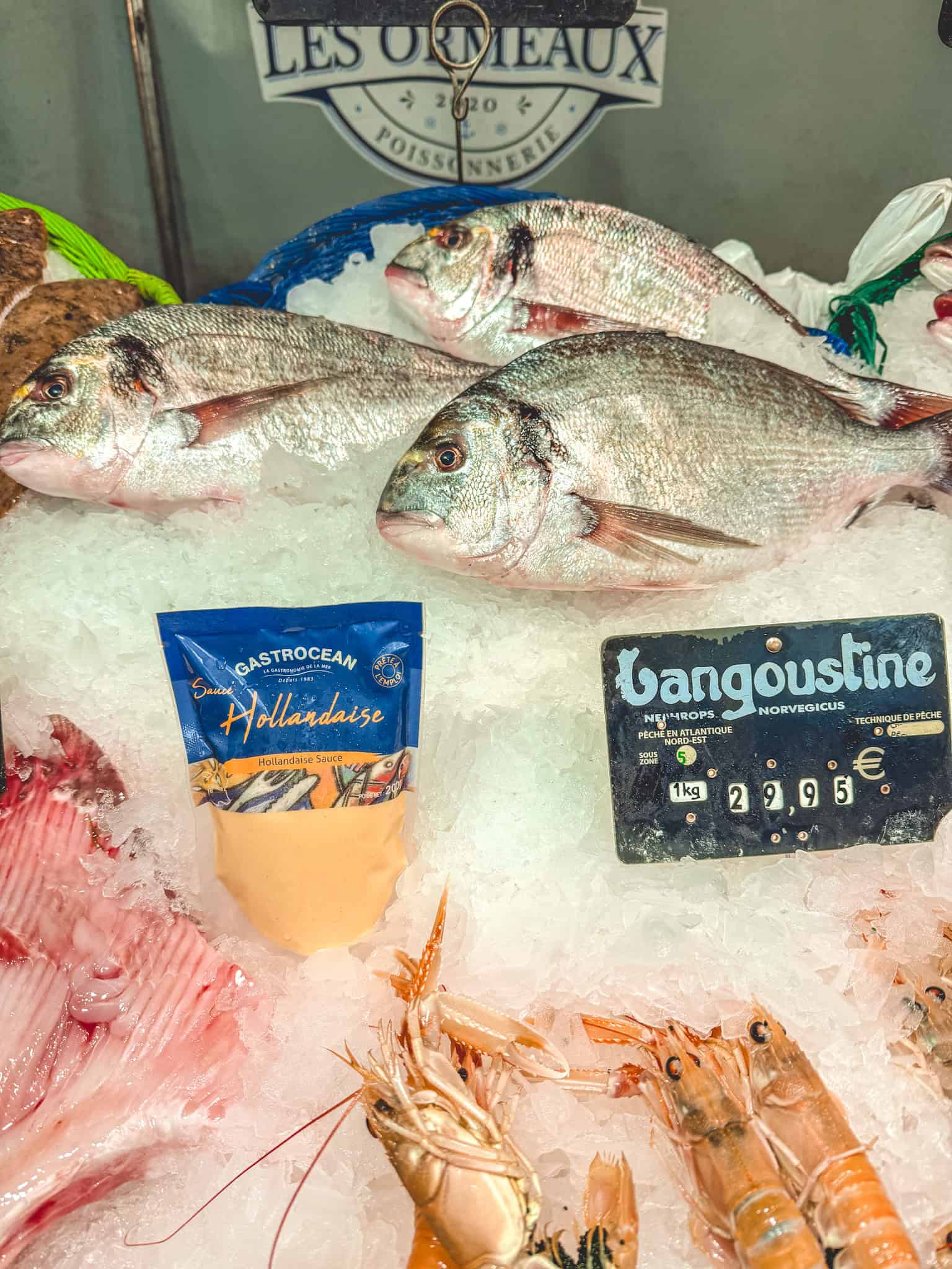 Fresh langoustine and sea bream displayed on ice at cooking class in Paris market tour