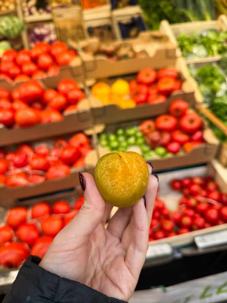 Trying a plum at French produce market during cooking class in Paris