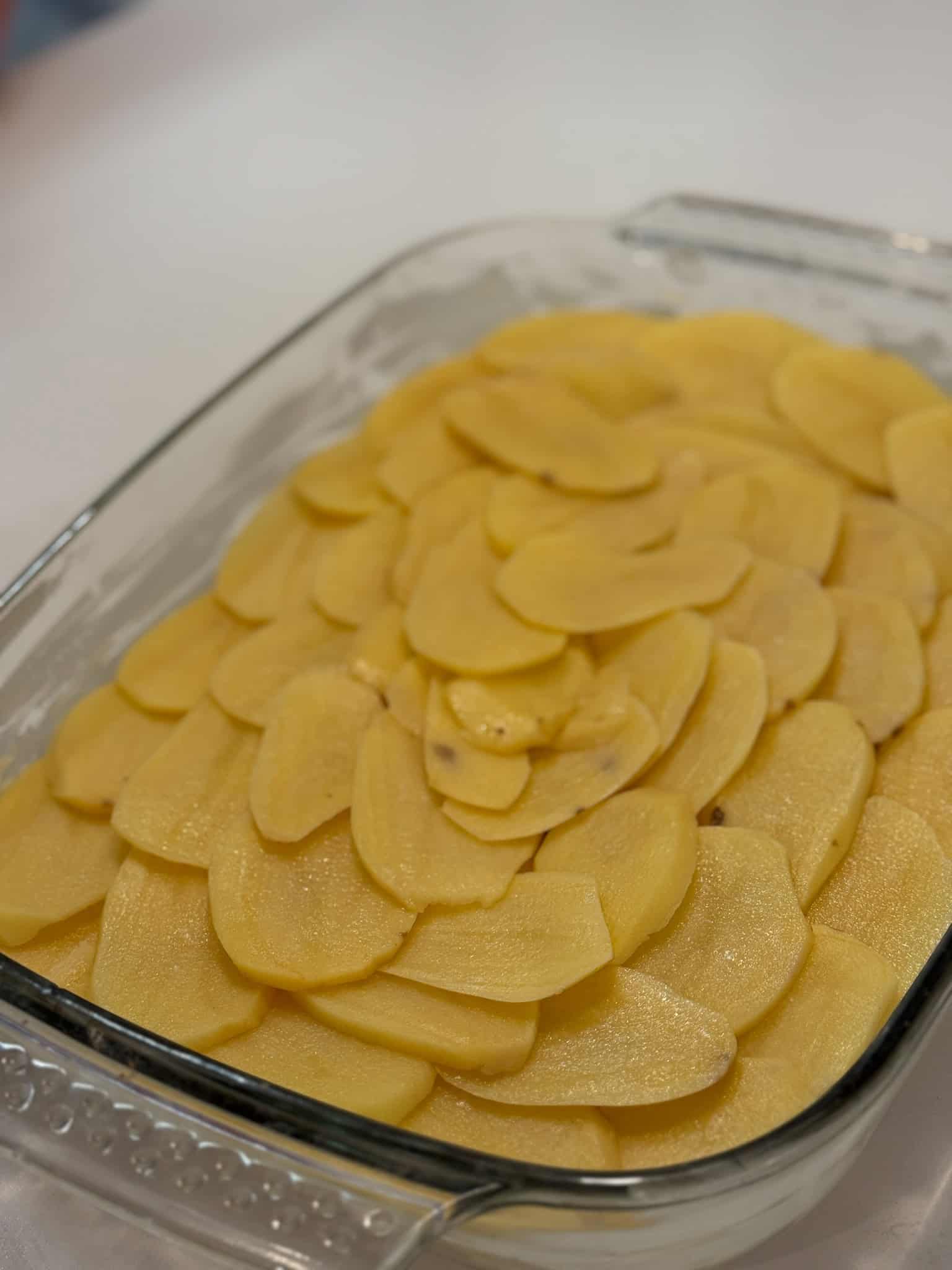 Thinly sliced potatoes arranged in decorative pattern for French potato gratin at culinary workshop