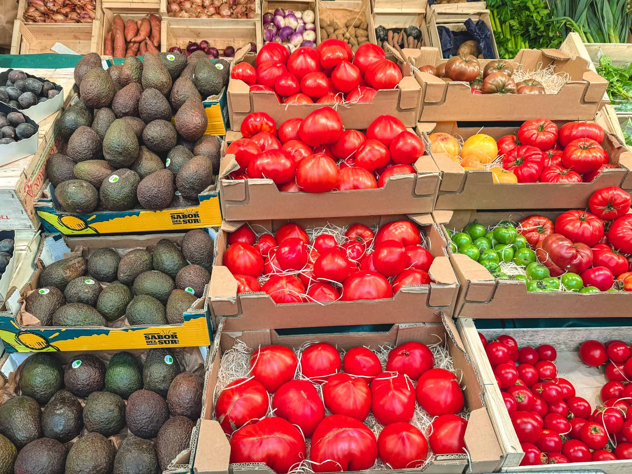 Fresh produce at Paris market with avocados, heirloom tomatoes, and colorful vegetables on display