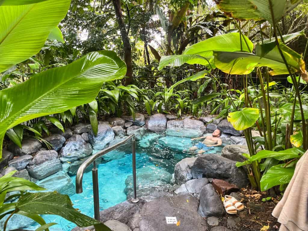 Natural hot springs pool surrounded by lush vegetation at Arenal Manoa Resort, thermal amenities for where to stay in La Fortuna with hot springs