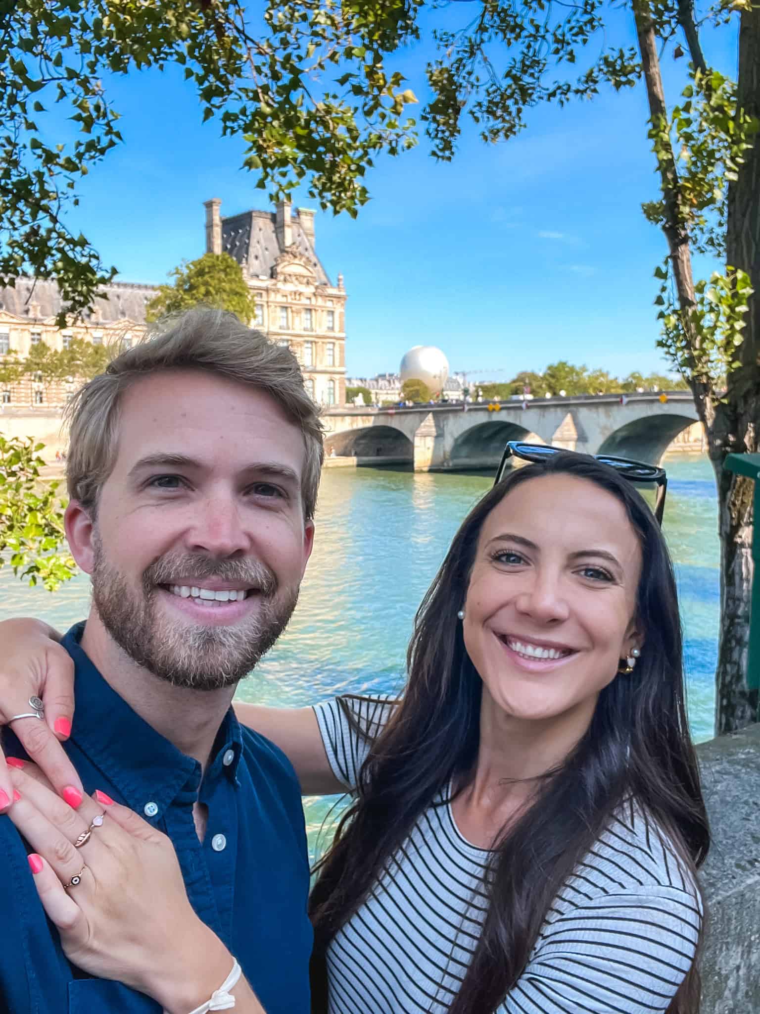 Tourists enjoying Paris along the Seine River with the Louvre in background despite travel disruptions