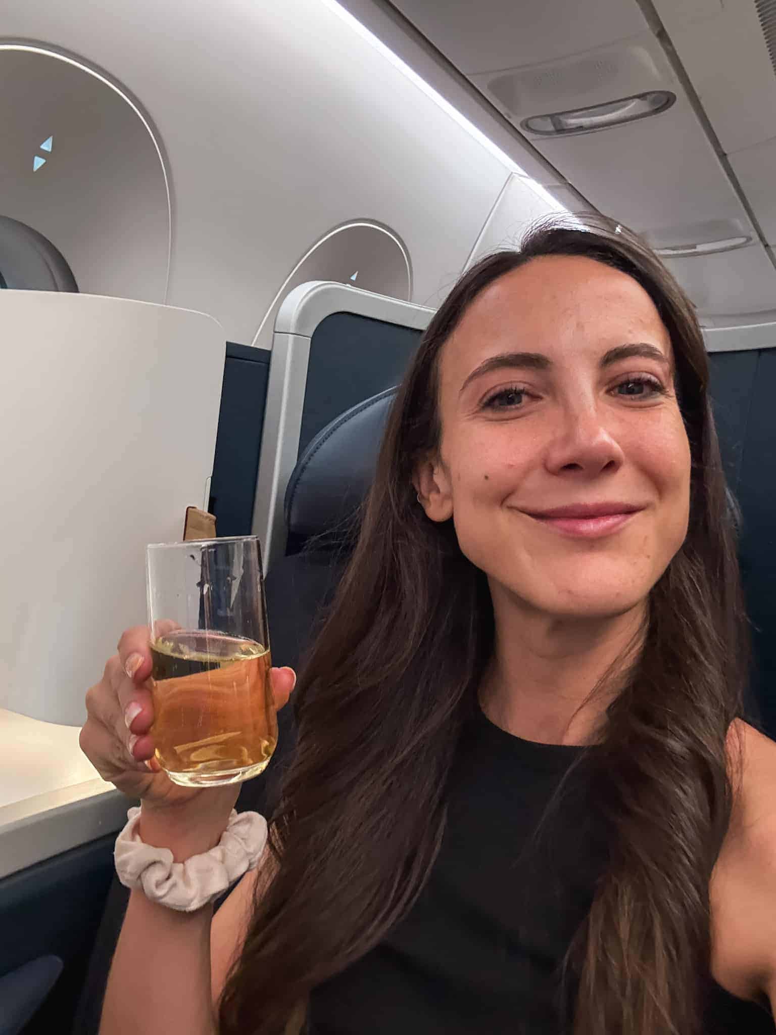 woman smiling with champagne in air france business class booked with the american express platinum card