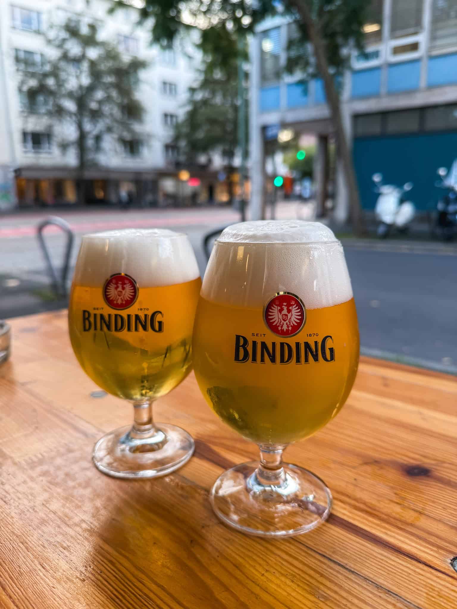 Two fresh Binding beers on outdoor patio overlooking Frankfurt streets, best places to drink beer in Frankfurt