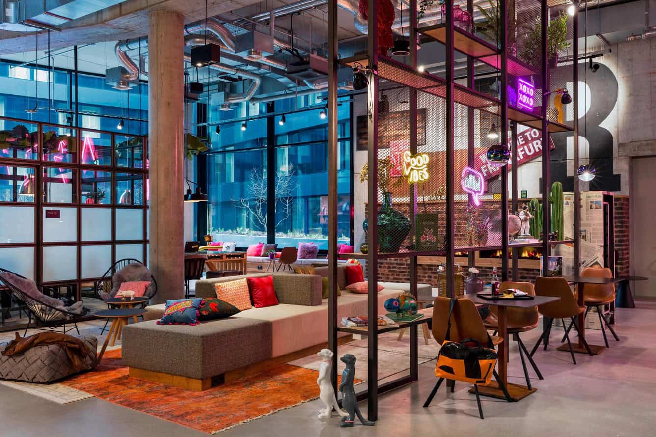 Vibrant Moxy Hotel lobby with neon signs and industrial design, perfect accommodation for one day in Frankfurt