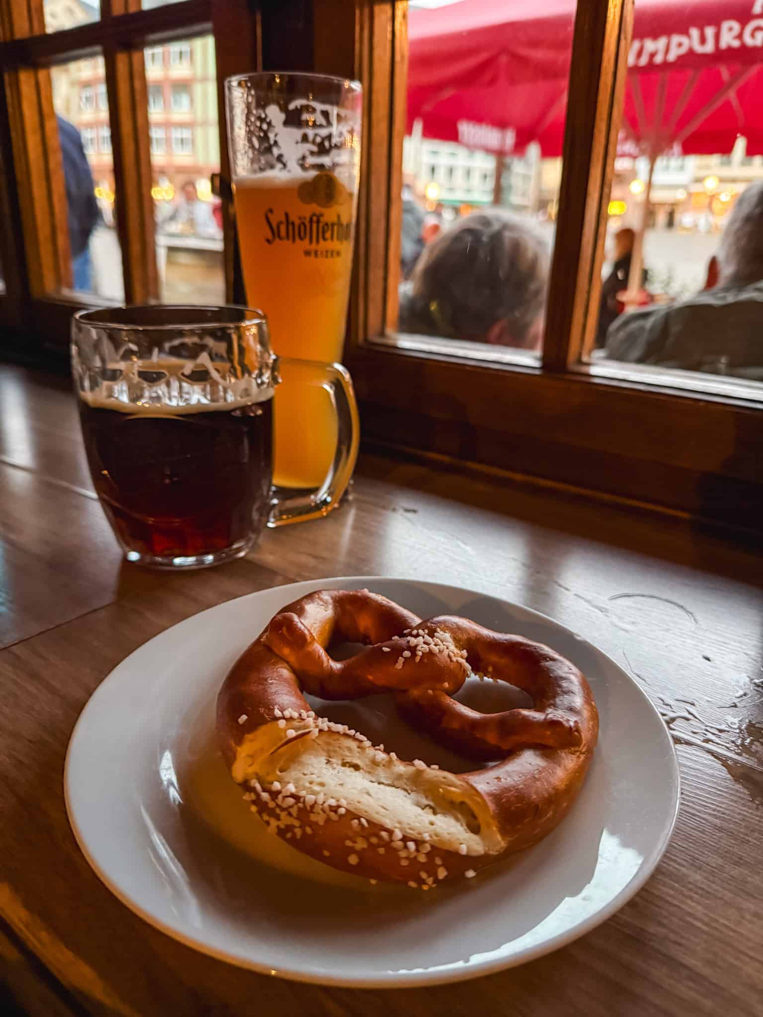 Traditional German pretzel with Schofferhofer beer overlooking the city, authentic Frankfurt food experience