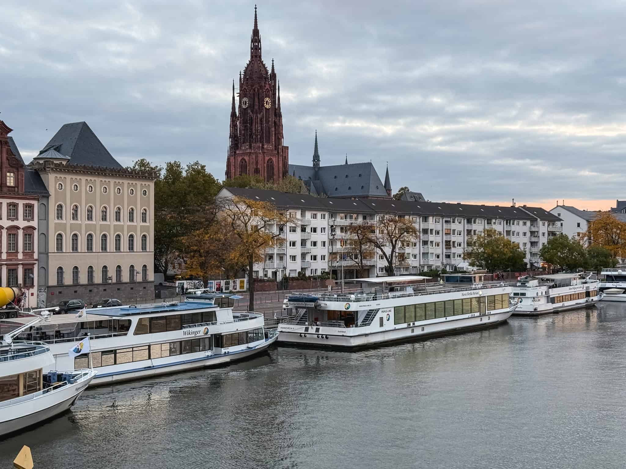 River Main with cathedral skyline and tour boats docked along the waterfront, scenic view for one day in Frankfurt