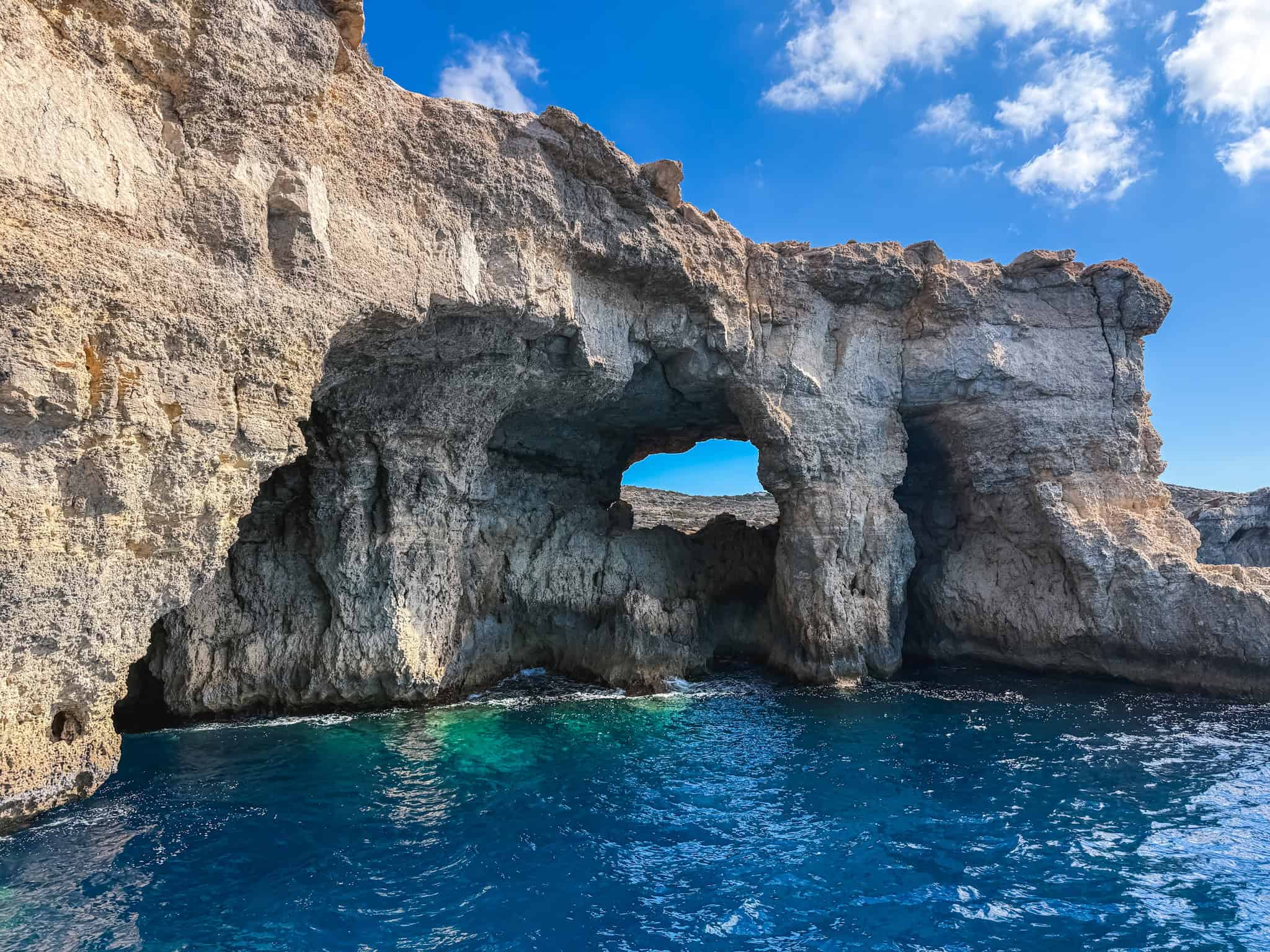 Dramatic natural limestone arch formation over crystal-clear Mediterranean waters along Malta's scenic coastal drives