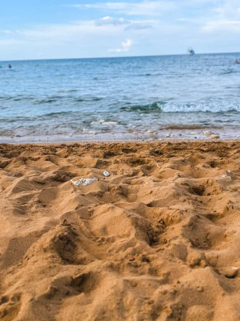 Sandy shoreline and Mediterranean waves at a peaceful Gozo beach, one of many coastal destinations reachable with a Malta rental car