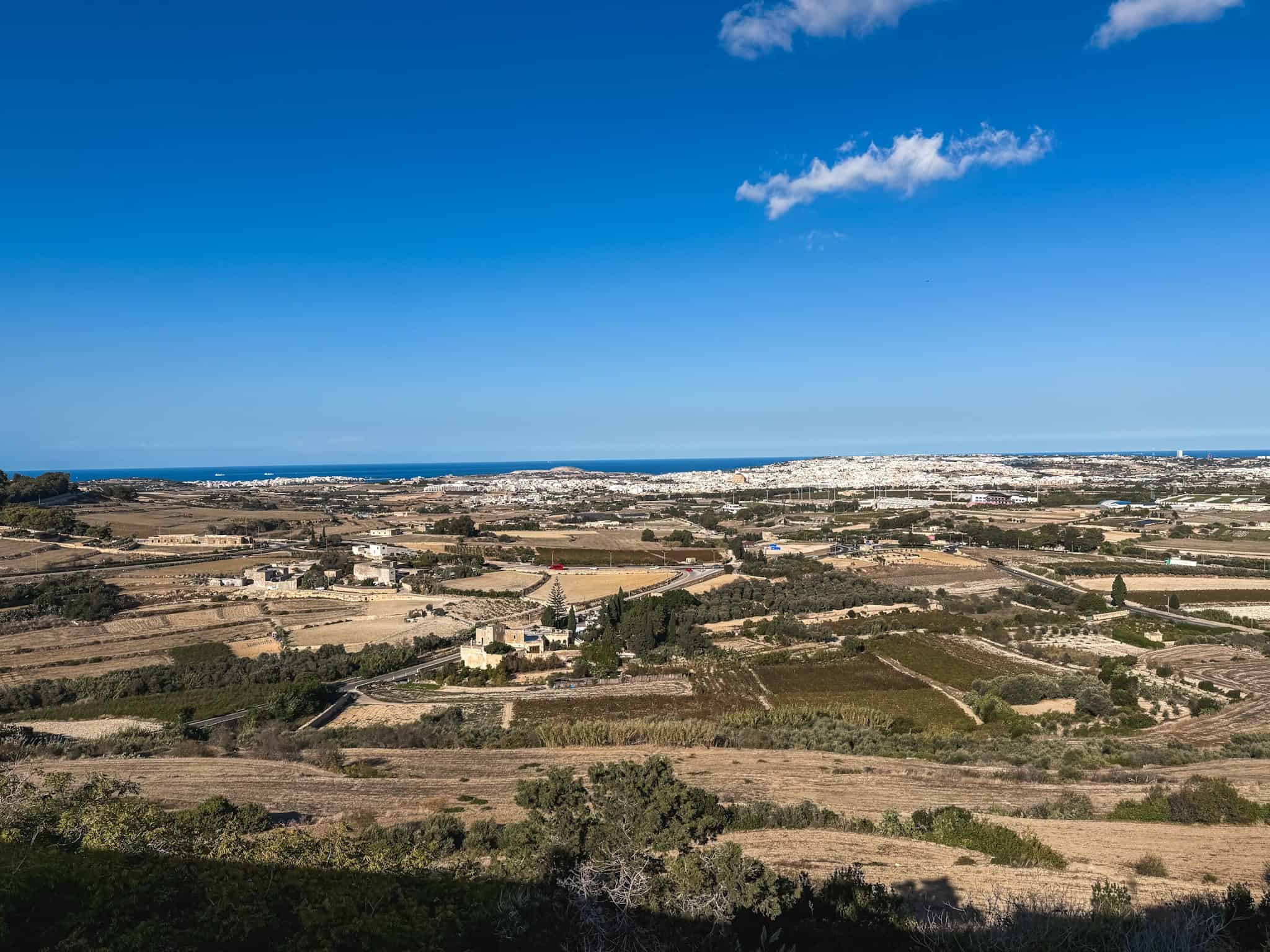 Panoramic countryside view showing why renting a car in Malta is ideal for exploring rural villages, terraced farms, and coastal roads leading to the Mediterranean Sea