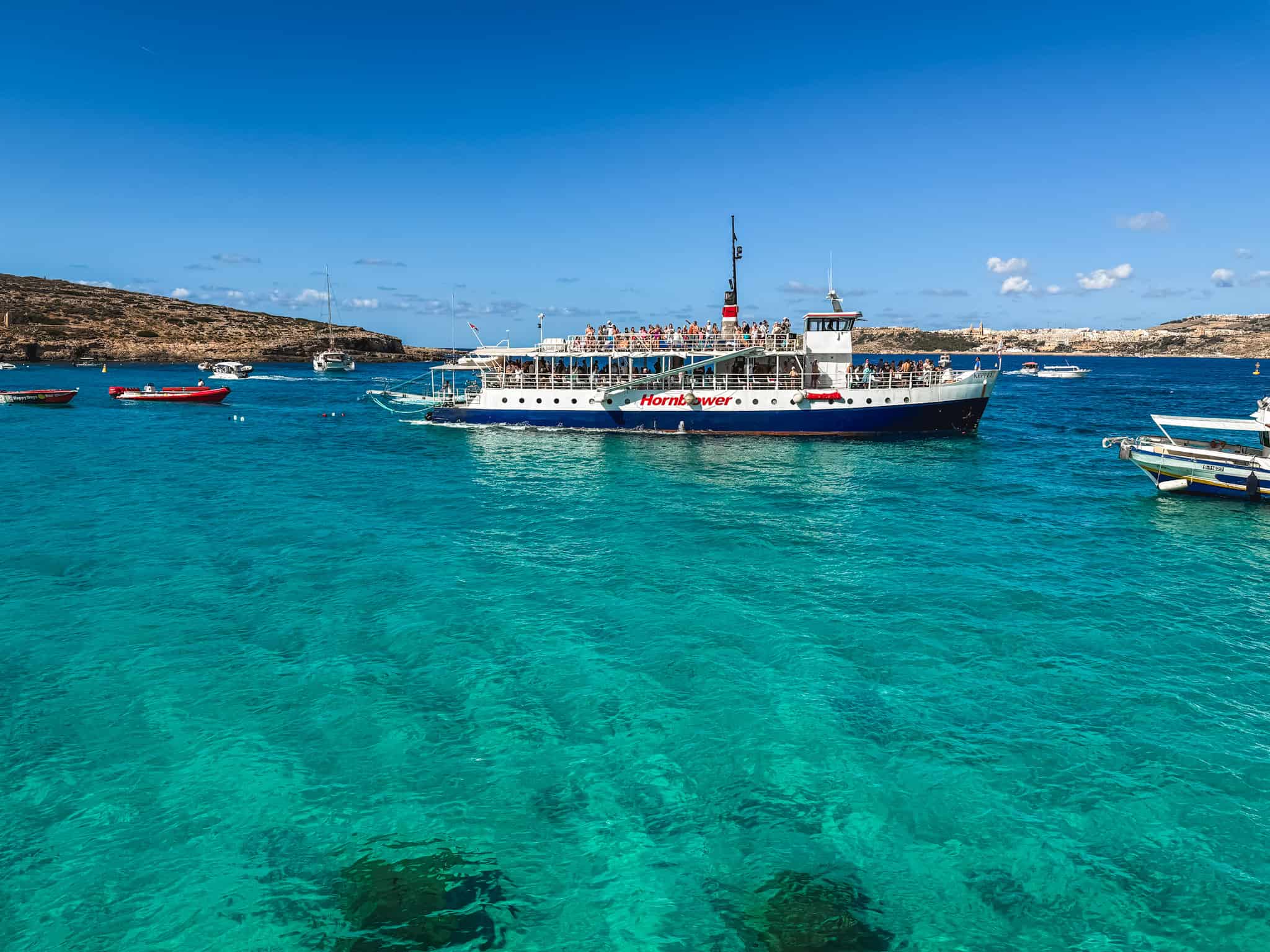 Malta boat tours boat anchored in the crystal clear waters near the Blue Lagoon