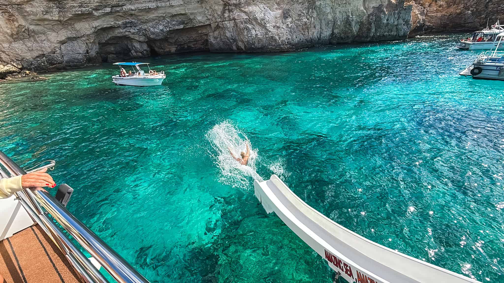 man sliding into the blue lagoon on a malta boat tour