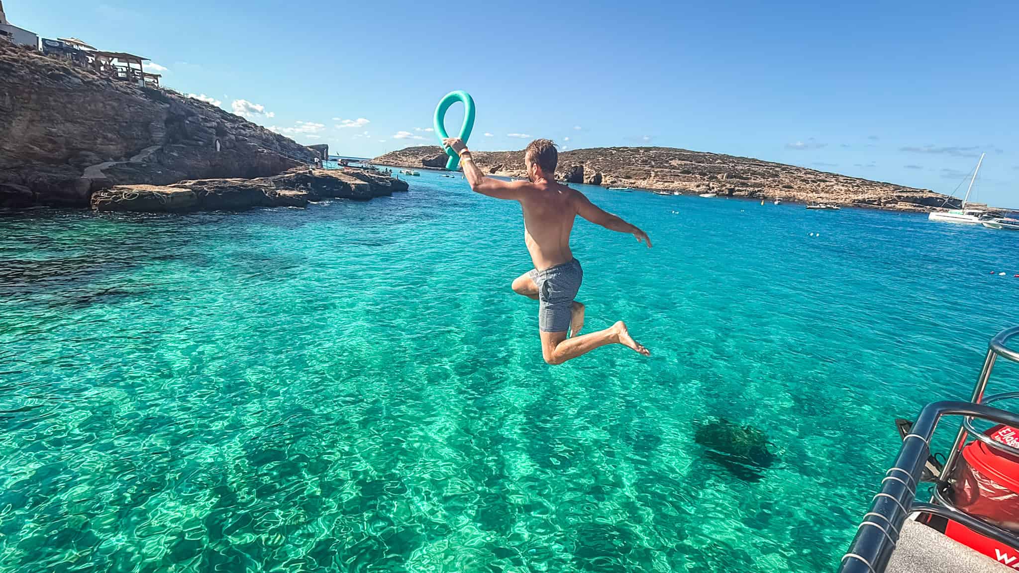Jumping into the crystal lagoon from a boat near Paradise Bay in Malta