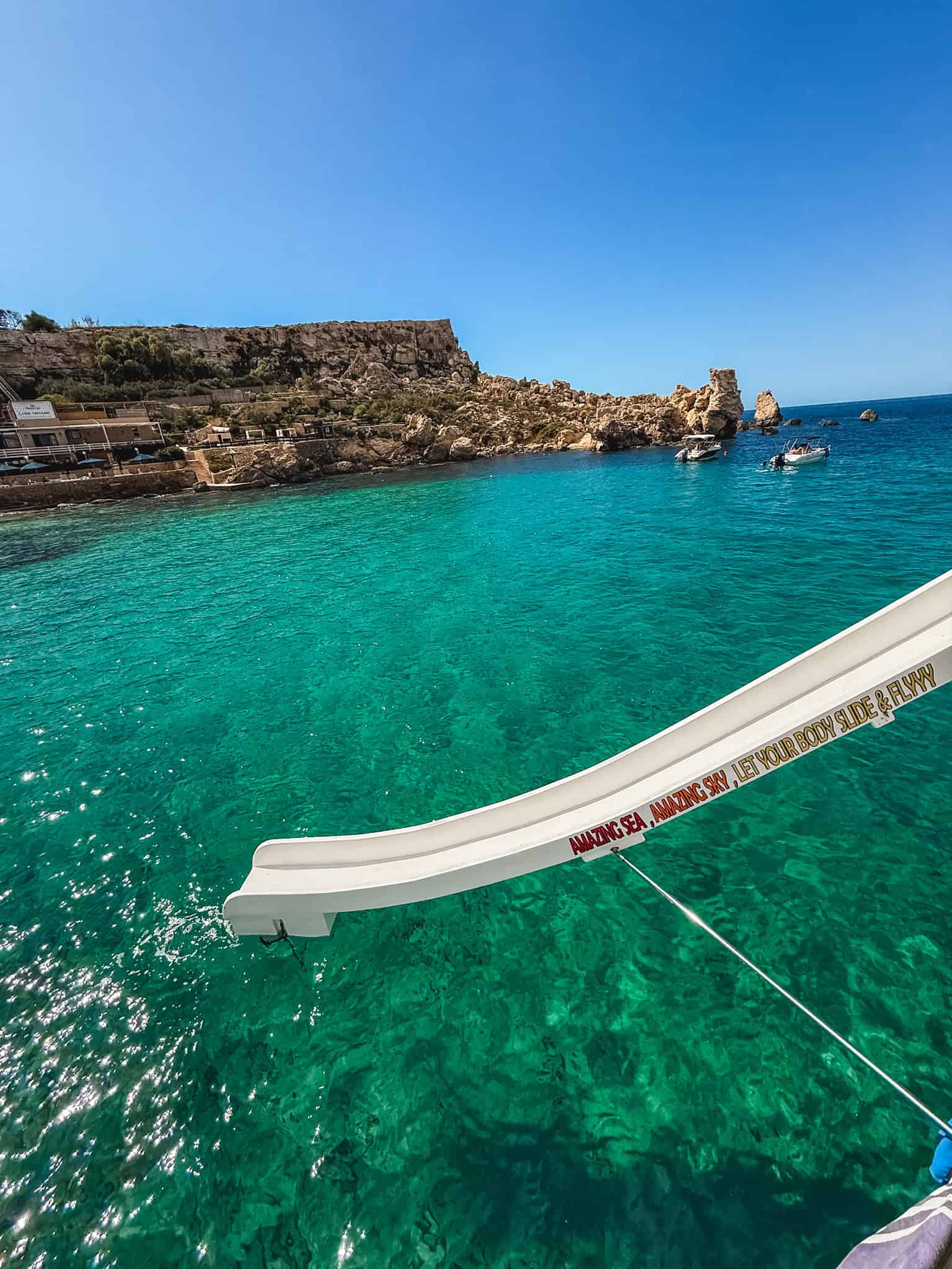 Boat slide into crystal lagoon waters at Paradise Bay during Comino boat trip