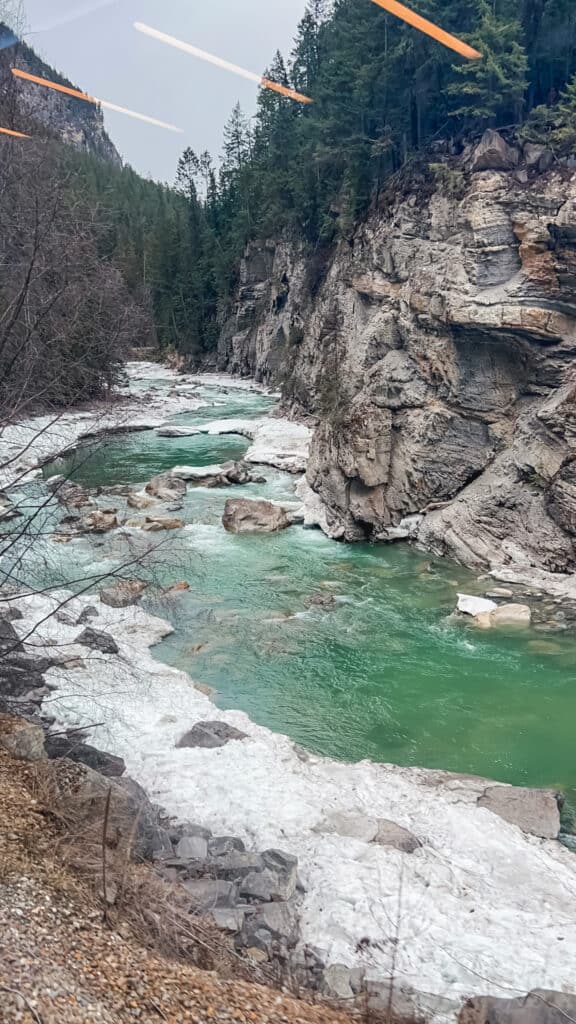 Turquoise glacial river flowing through rocky canyon with layered cliff formations on Journey through the Clouds route
