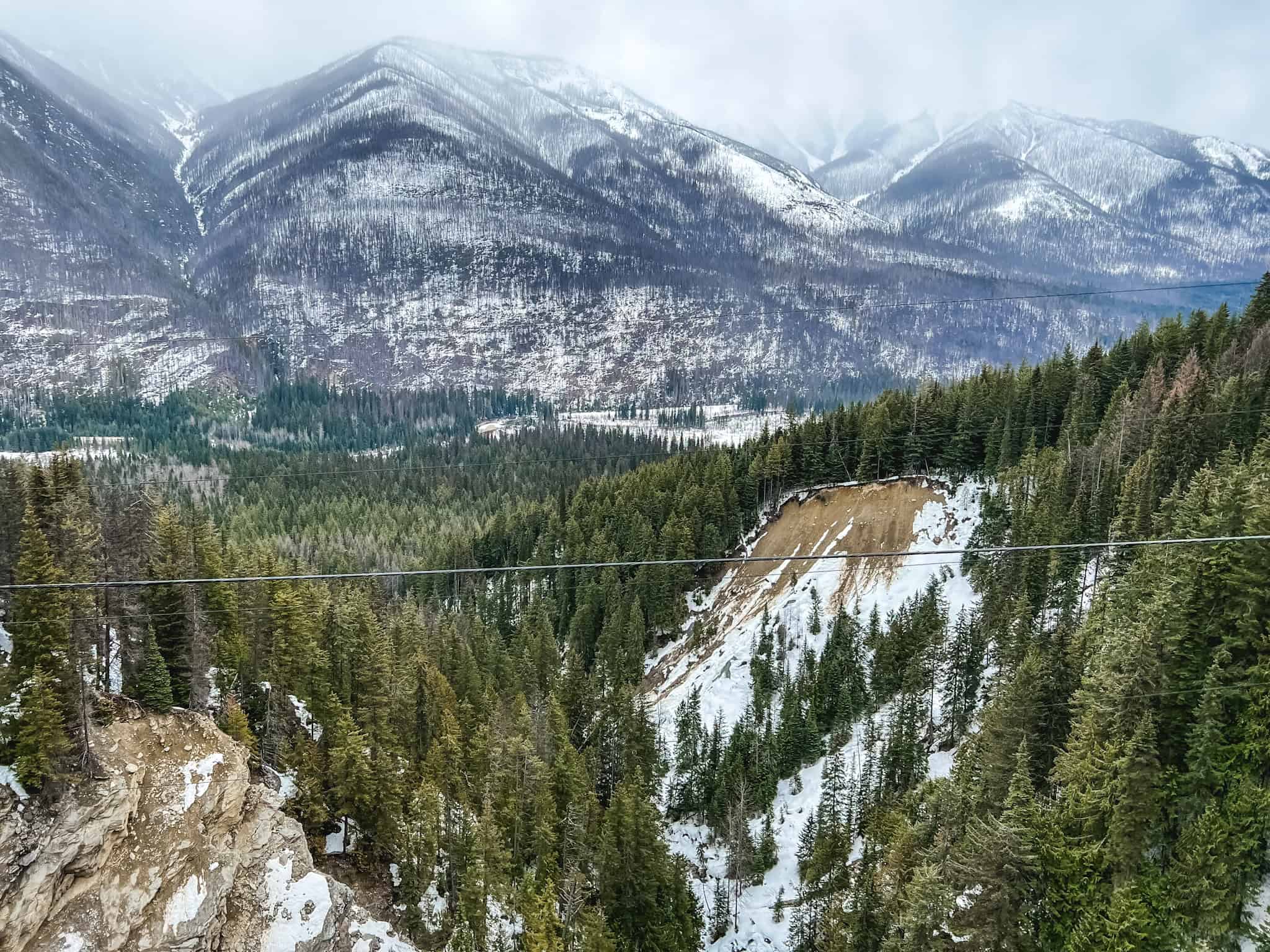 Snow-covered Canadian Rockies mountain range with pristine evergreen forests visible from luxury sightseeing train in winter