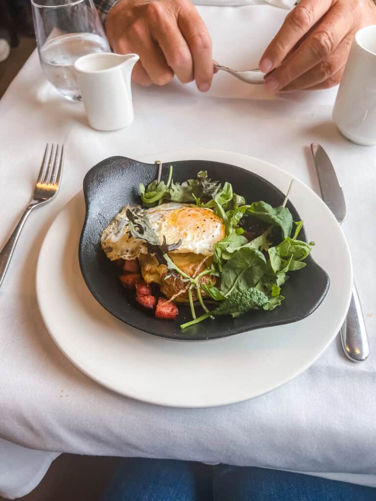 Rocky Mountaineer train BC farmer sausage breakfast with fried egg, crispy hash browns, and arugula on GoldLeaf dining car